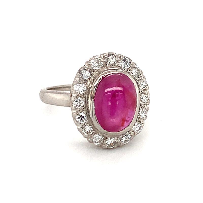 One mid-century star ruby and diamond palladium ring centering one oval cabochon, pinkish-red star ruby weighing approximately 3 ct. with strong asterism (6-ray star). Features an Art Deco design influence and enhanced by 16 round brilliant cut
