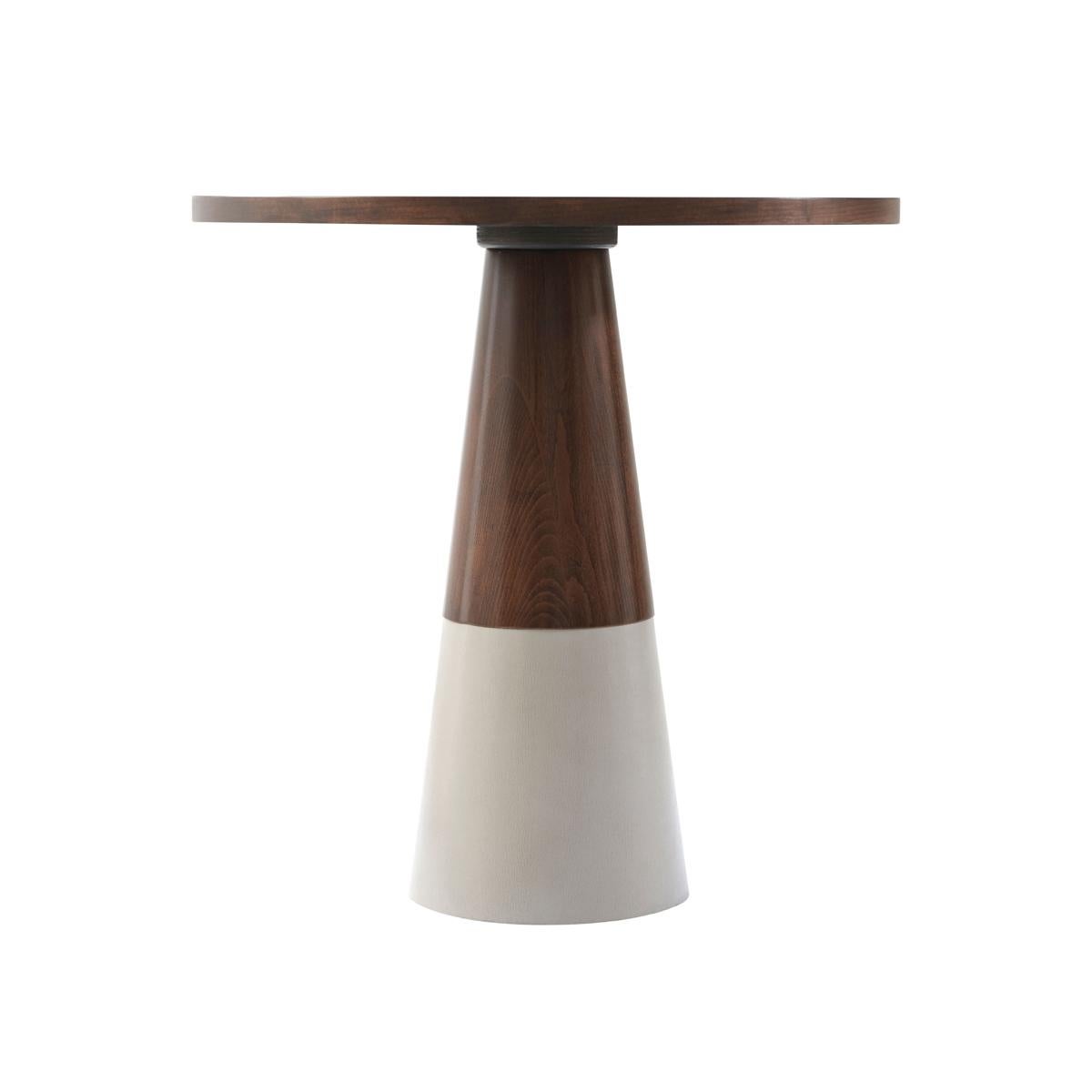 In a light almond finish to the starburst cherry veneered top with a central metal inlaid decorative disc. Raised on a tapered column pedestal wrapped in a grey leather detail.

Dimensions: 20