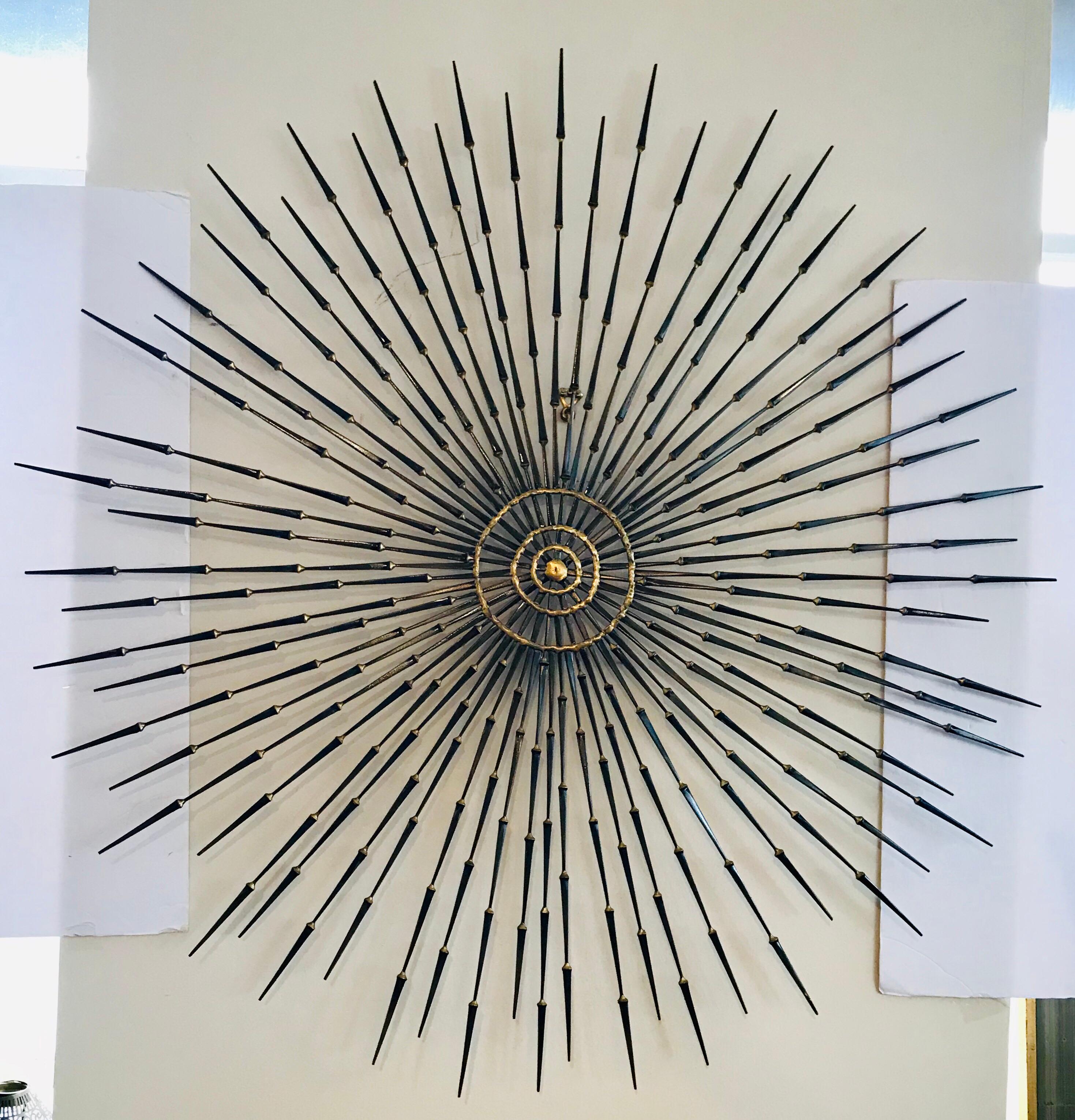 A large Brutalist sunburst with starburst overlay nail art wall sculpture by Ron Schmidt. It is made up of
copper, metal, brass and iron. This sculpture features a multi-planar design with brass welded iron nail rays radiating sunburst-style from a