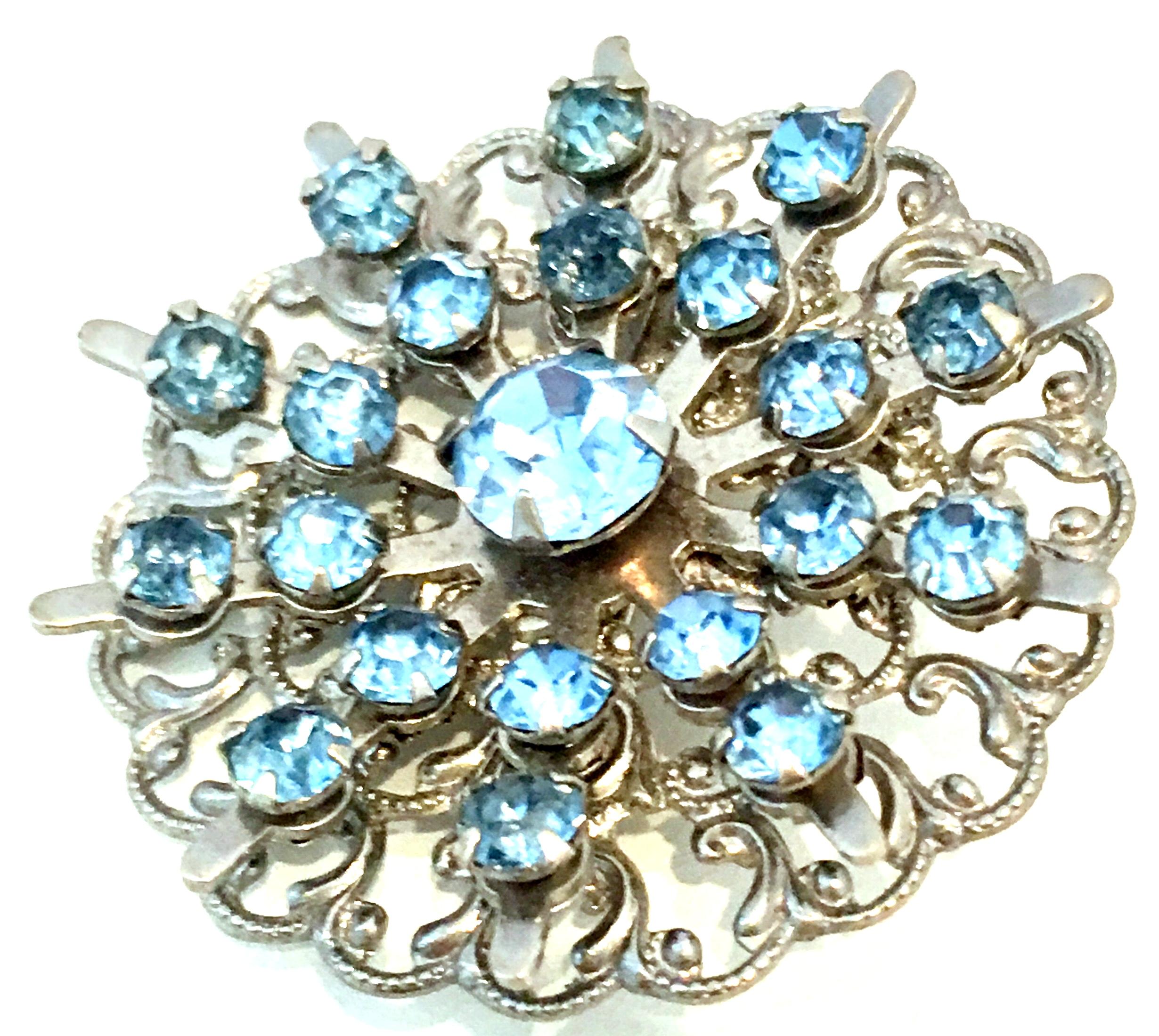 Mid-20th Century Sterling Silver & Austrian Crystal Dimensional Brooch. This unique dimensional brooch features stamped and filigree sterling silver with brilliant cut and faceted fancy prong set sapphire blue Austrian crystals. The large center