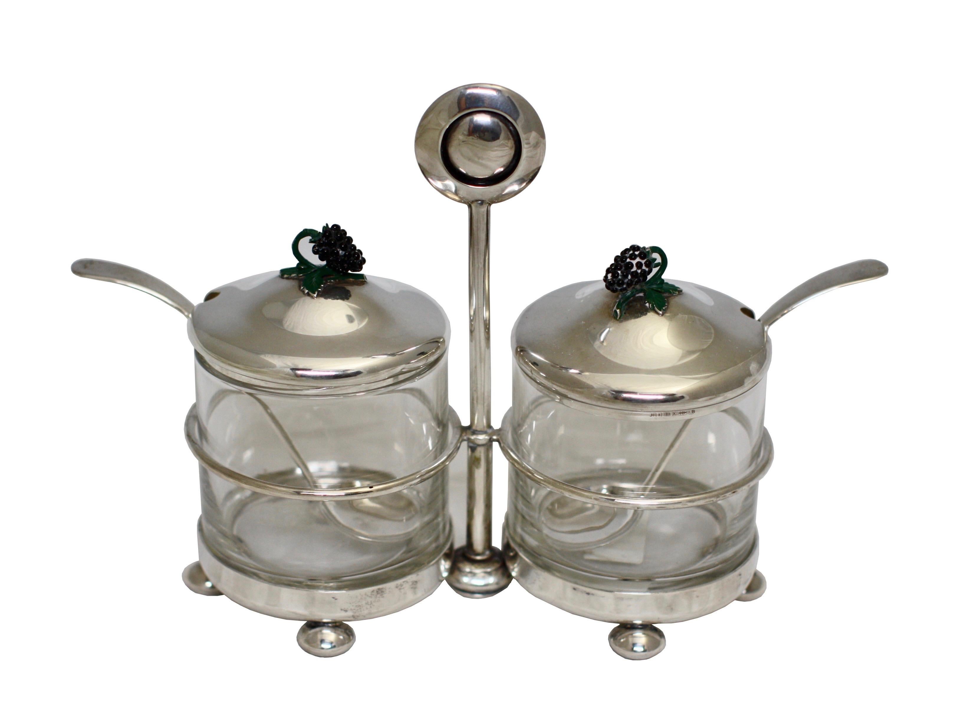 Midcentury sterling silver & enamel cruet set
A sterling silver & enamel glass-mounted cruet set,
the circular frame on ball feet, with enameled finials on the domed covers with labels,
marked on covers & reverse of spoons with mark