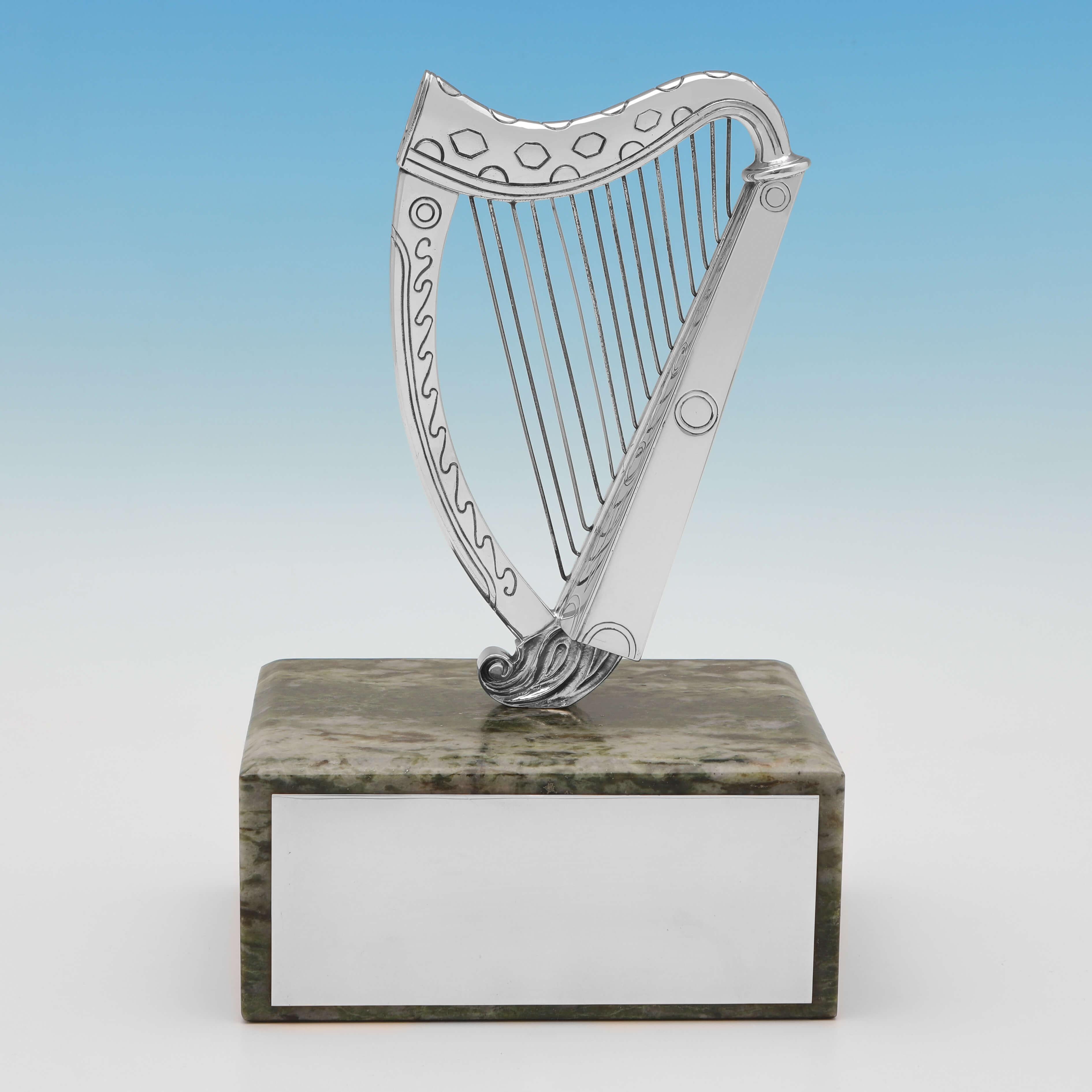 Hallmarked in London in 1970 by Barnards, this charming, Sterling Silver Model of a Harp, is well modelled, and presented on a green marble base with a silver plaque for engraving. The harp is decorated with a geometric engraved design. 

It would