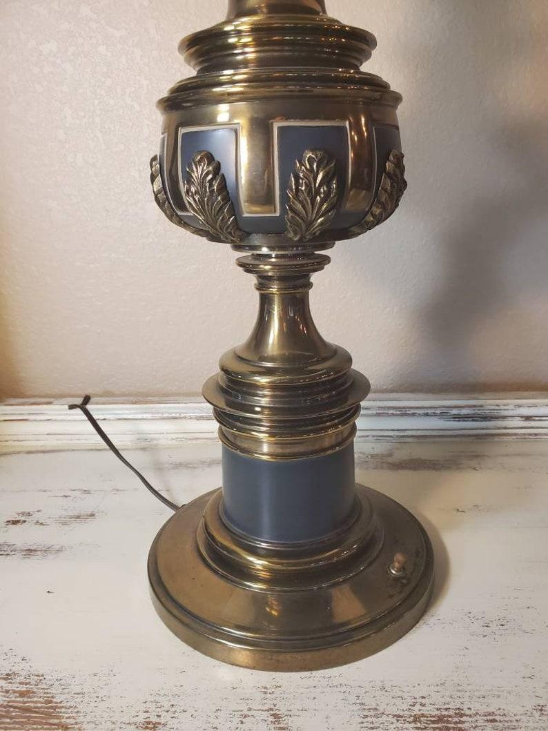 A beautiful tall mid-20th century Stiffel table lamp in brass with matte black enamel accents and foliate leaf detailing. Having an urn-form turned brass central standard, rising on round base with conveniently located on/off switch. Accompanied