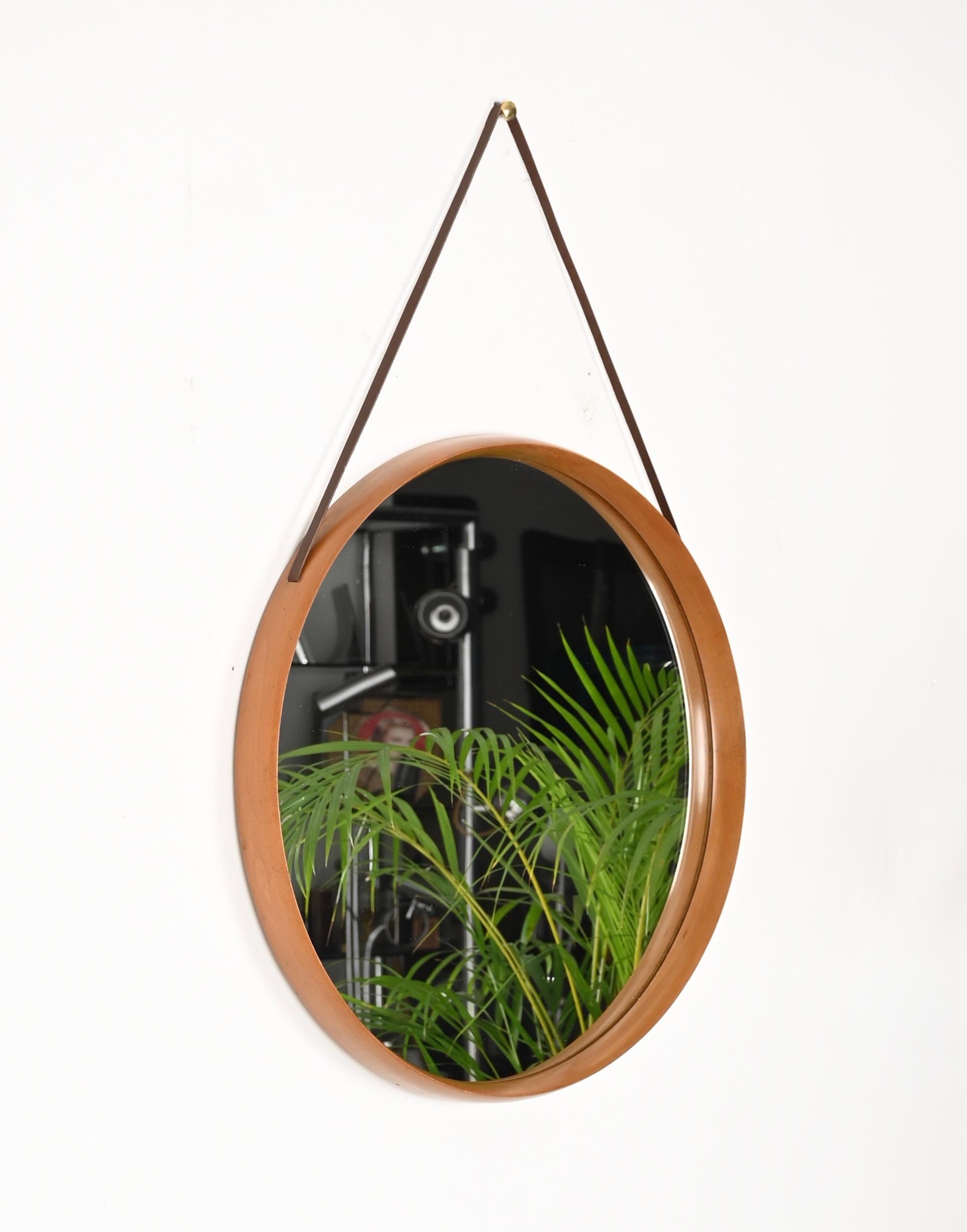 Amazing mid-Century round mirror made in solid walnut with a leather cord. This charming mirror was designed by Stildomus in Italy during the 1960s. 

The frame of the mirror is made in a lovely blonde walnut that pairs amazingly with the darker