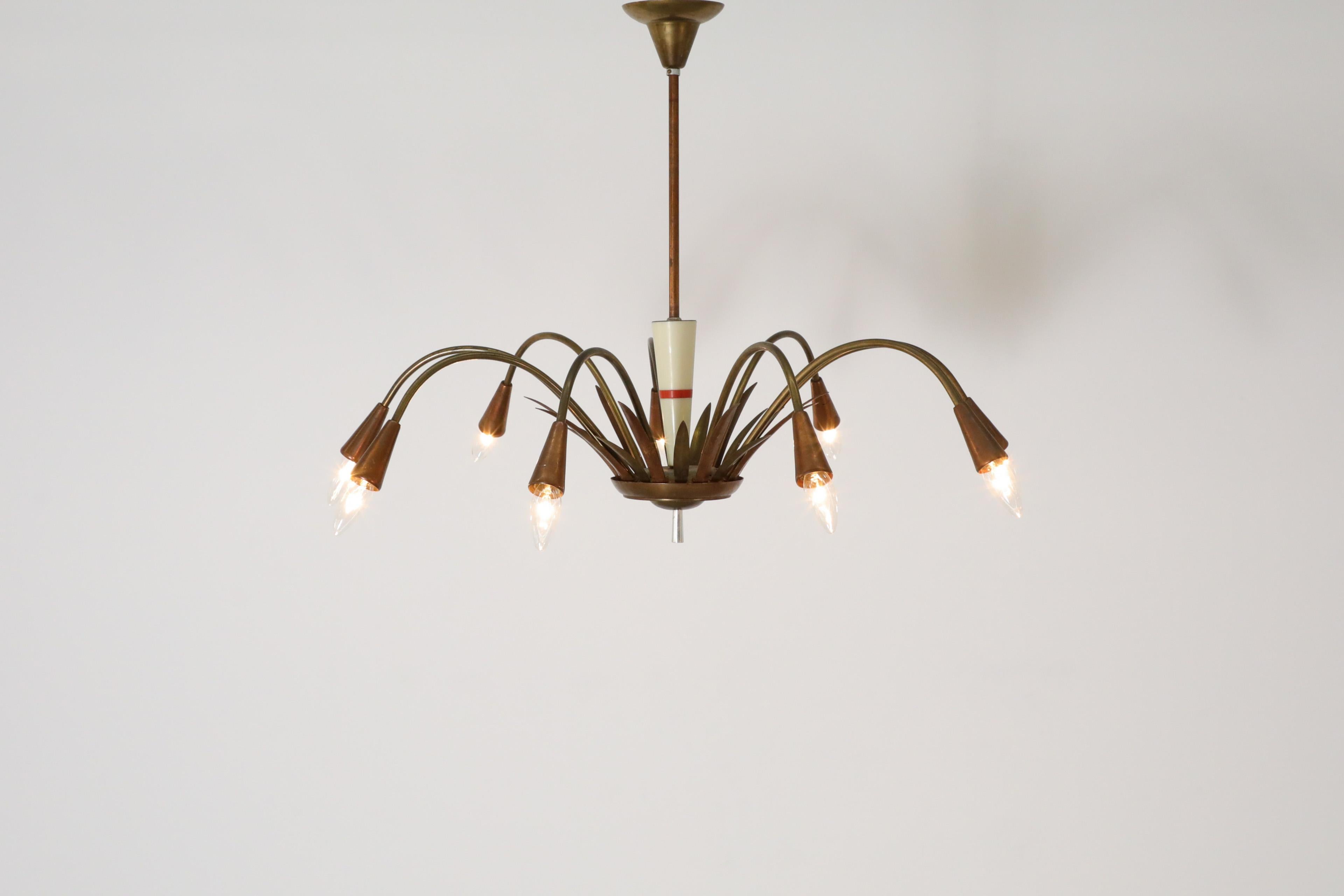 Mid-Century Art Deco inspired copper and brass chandelier with 8 curved arms and attractive, decorative features using both metals. The leaf design at the base surrounds the white conical stem and features a red stripe. Sockets fit European