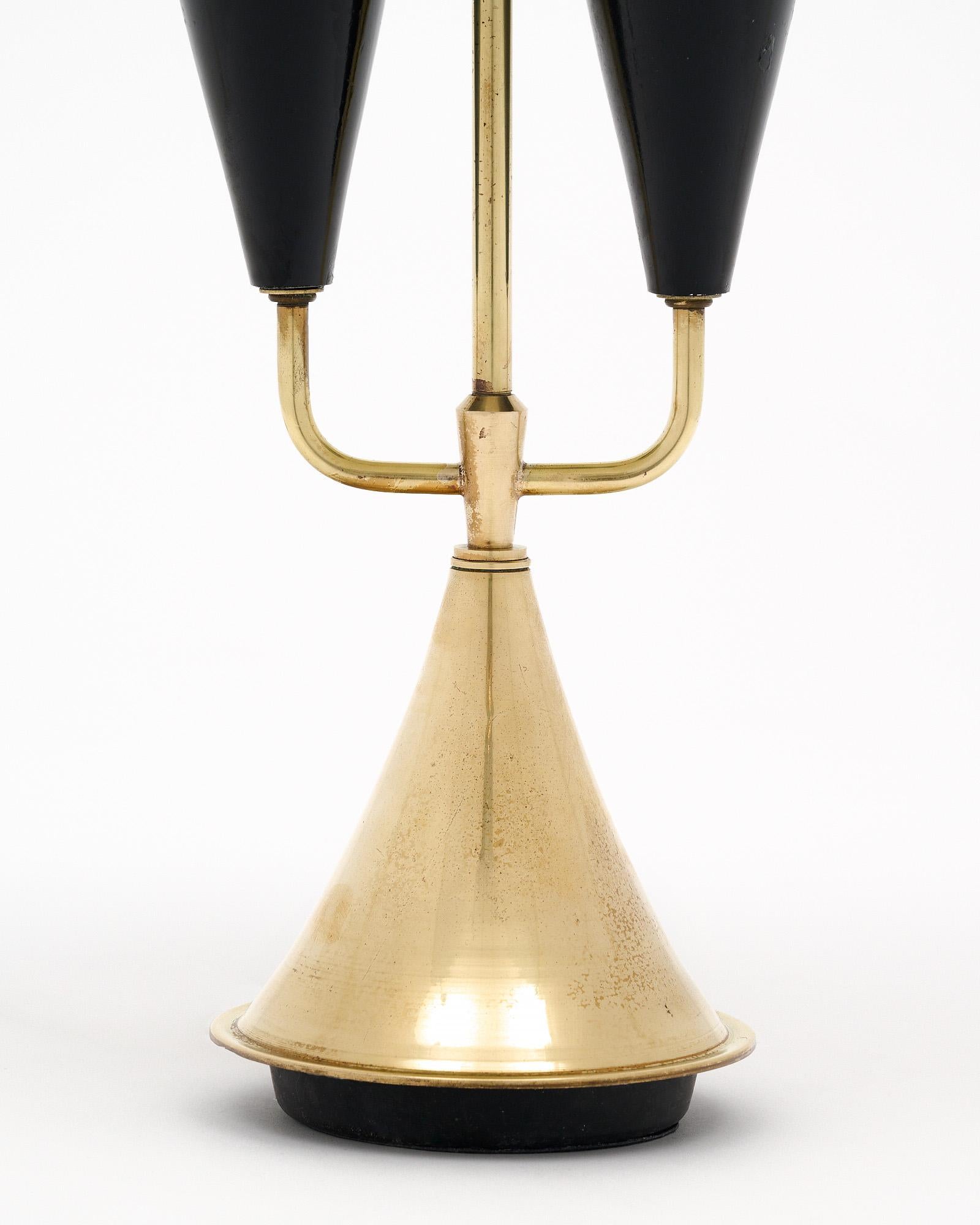 Single table lamp from Italy in the mid-century style. This piece features a brass structure with lacquered metal shade in black. The shade matches the conical candelabra lights. This is an elegant and stylish piece, perfect for a side table or