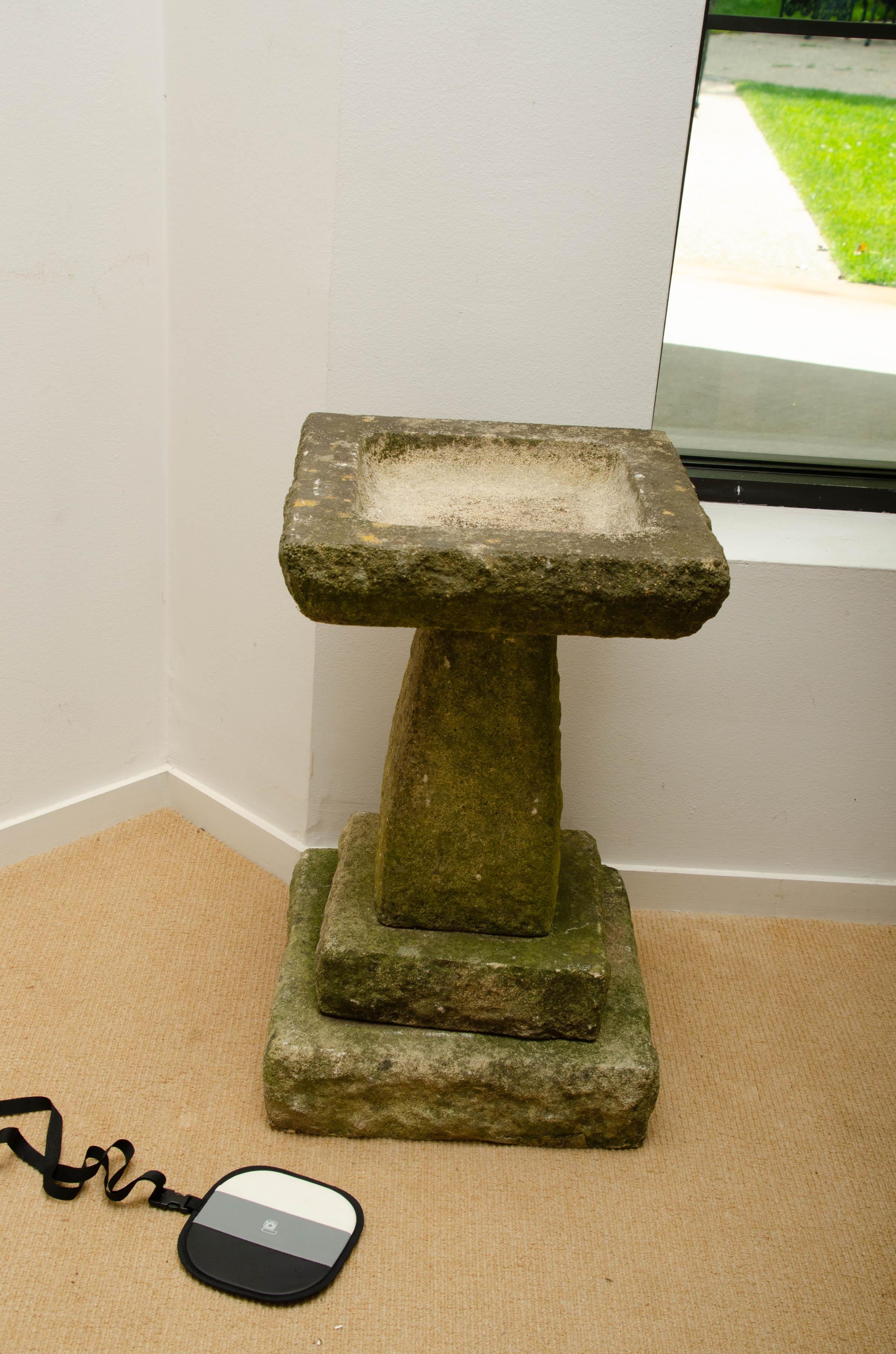Midcentury stone bird bath with carved stone composition with square top.