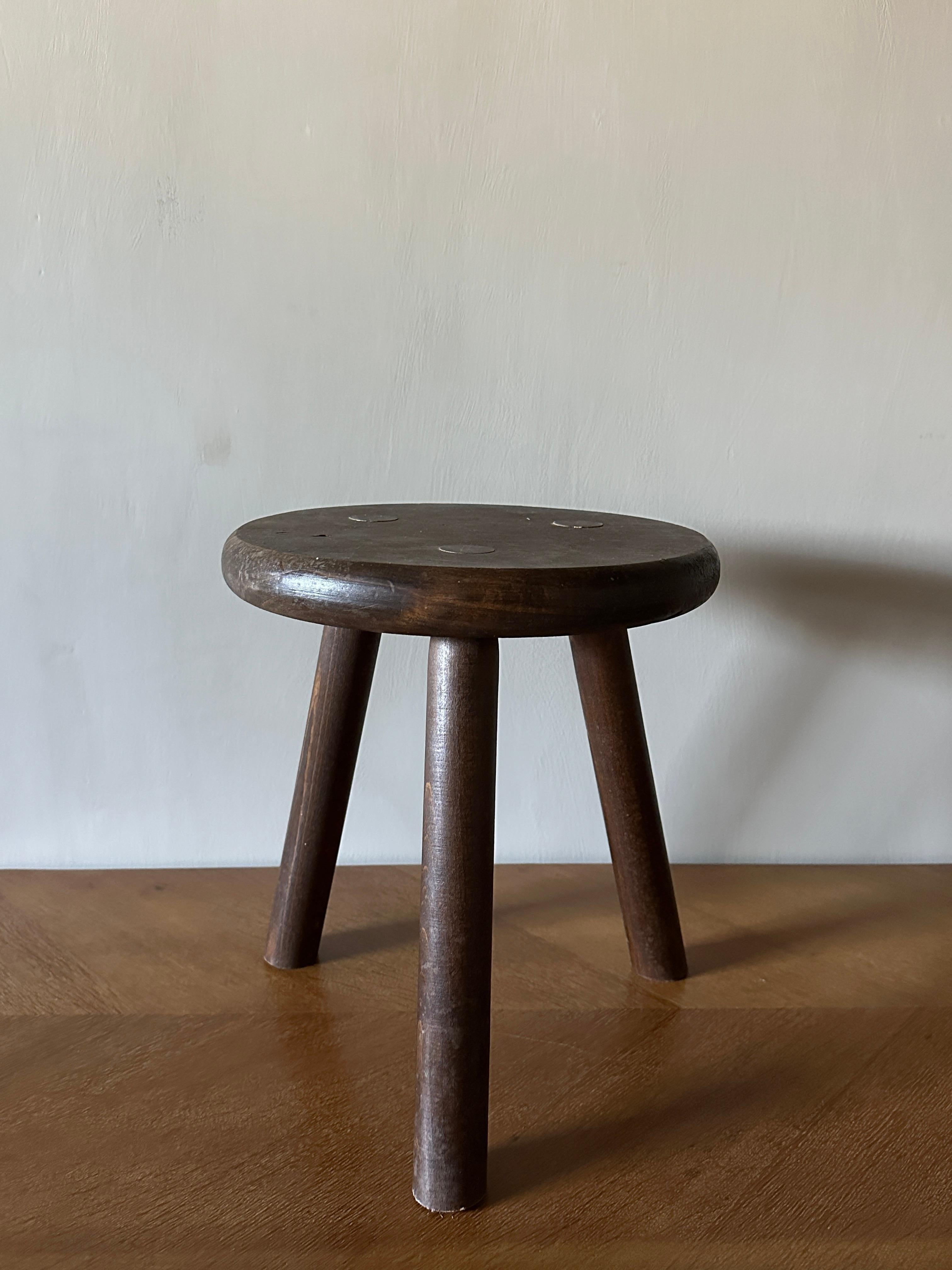 A Mid-Century wooden stool with three legs. By anonymous designer in France, c. 1960s. Wear consitnet with age and use. 