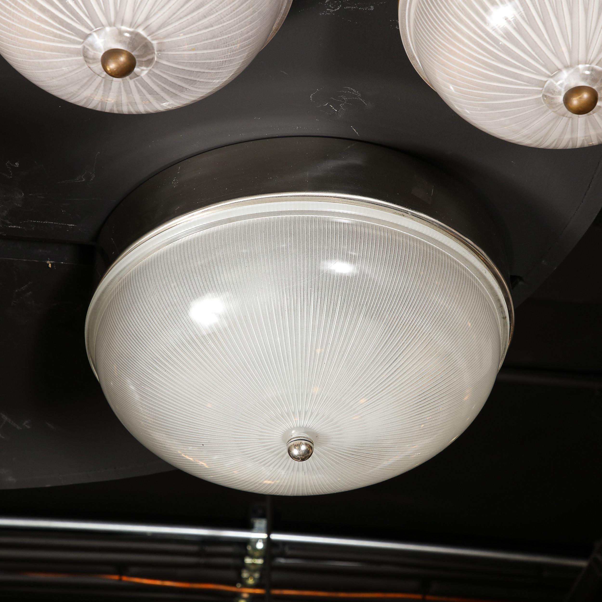 This elegant Mid-Century Modern flush mount chandelier was realized in Czechoslovakia circa 1950. It features a convex domed body with a striated starburst pattern embedded in the glass- consisting of an abundance of rays exploding from the center