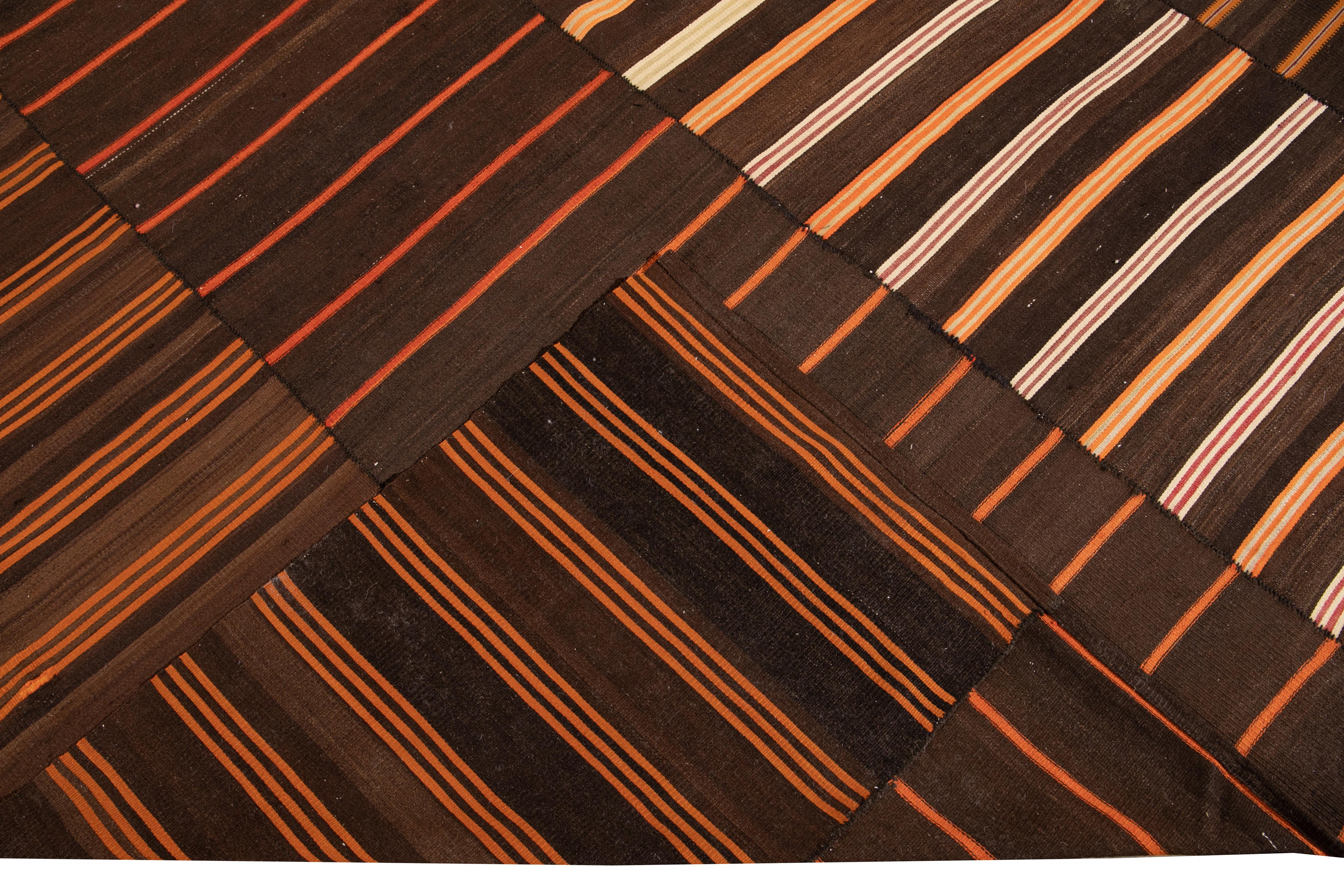 Beautiful vintage oversize flat-weave handmade wool rug. This Kilim rug has a brown field and multi-color accents in a gorgeous geometric abstract stripe design.

This rug measures: 11'9