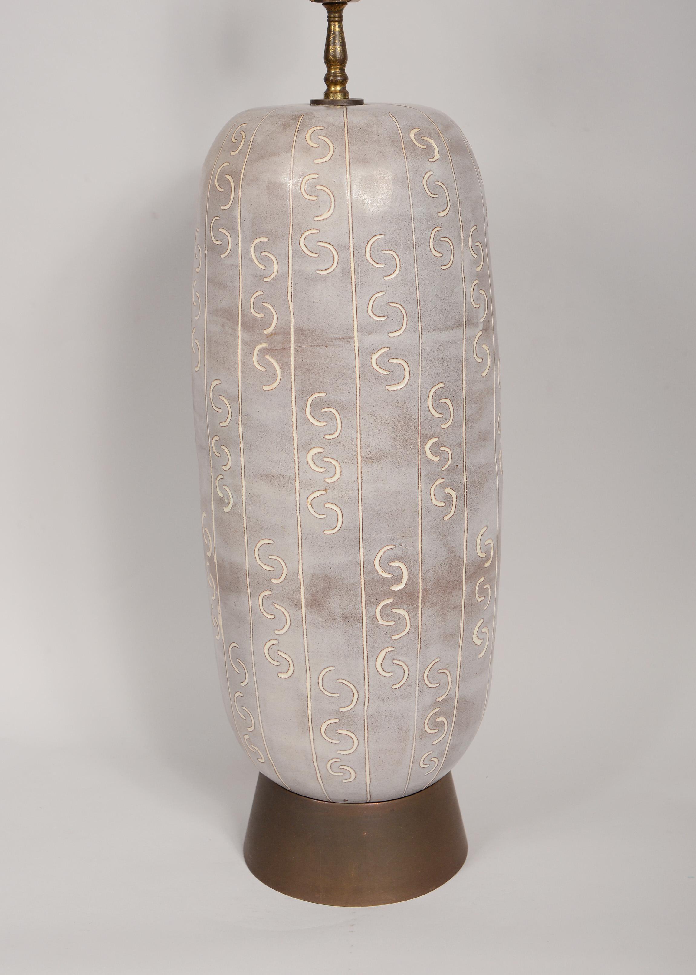 Studio ceramic table lamp with brass base. This lamp has a repetitive sgraffito design around it. This will be rewired with a cloth cord and three way socket. Height listed is to the top of the harp. The height to the bottom of the socket is 21.5