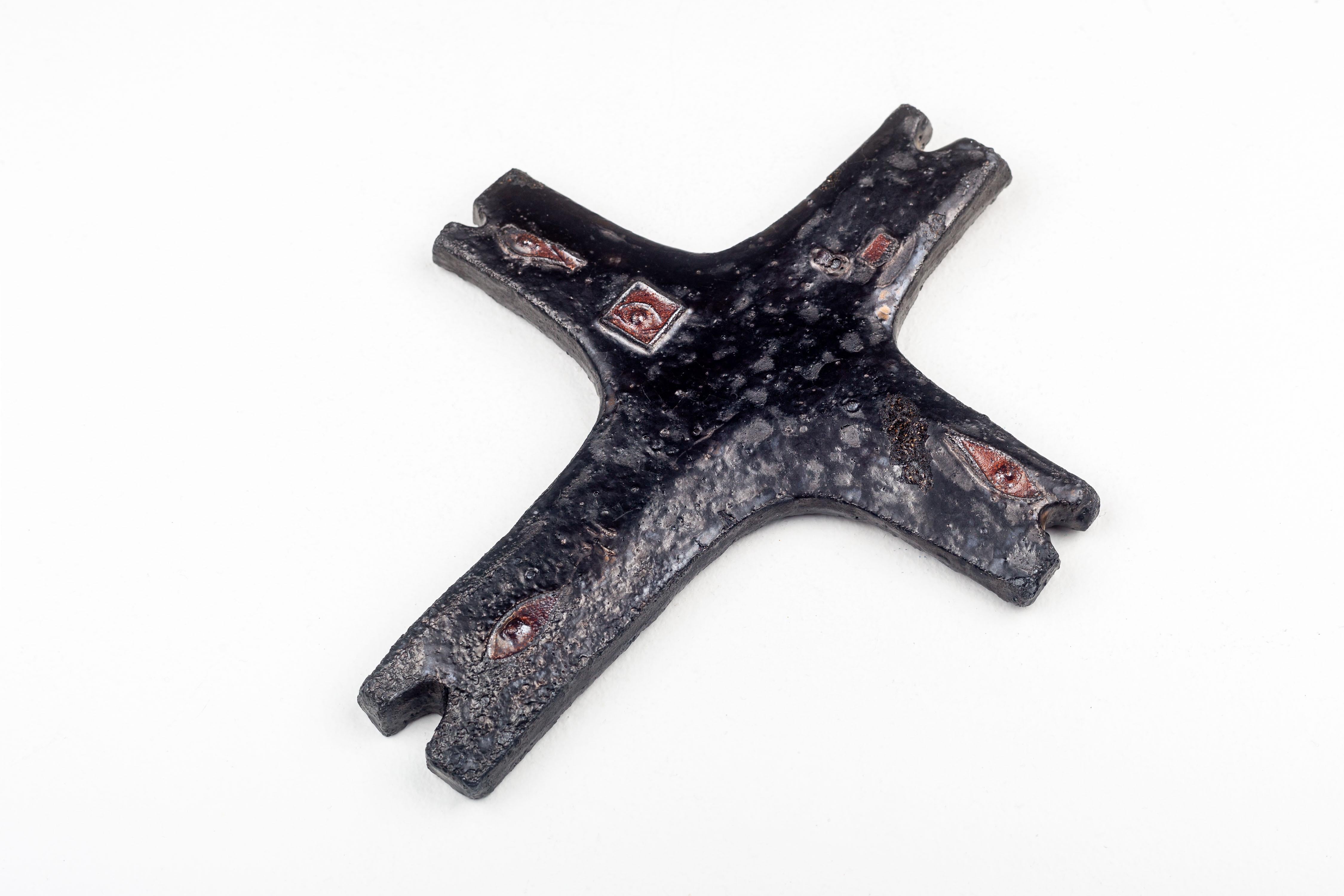 Dieses Keramikkreuz ist ein bemerkenswertes Beispiel für die europäische Studiotöpferei der Mitte des Jahrhunderts und spiegelt das Interesse dieser Epoche an abstrakten und symbolischen Formen wider. Das von einem geschickten Künstler