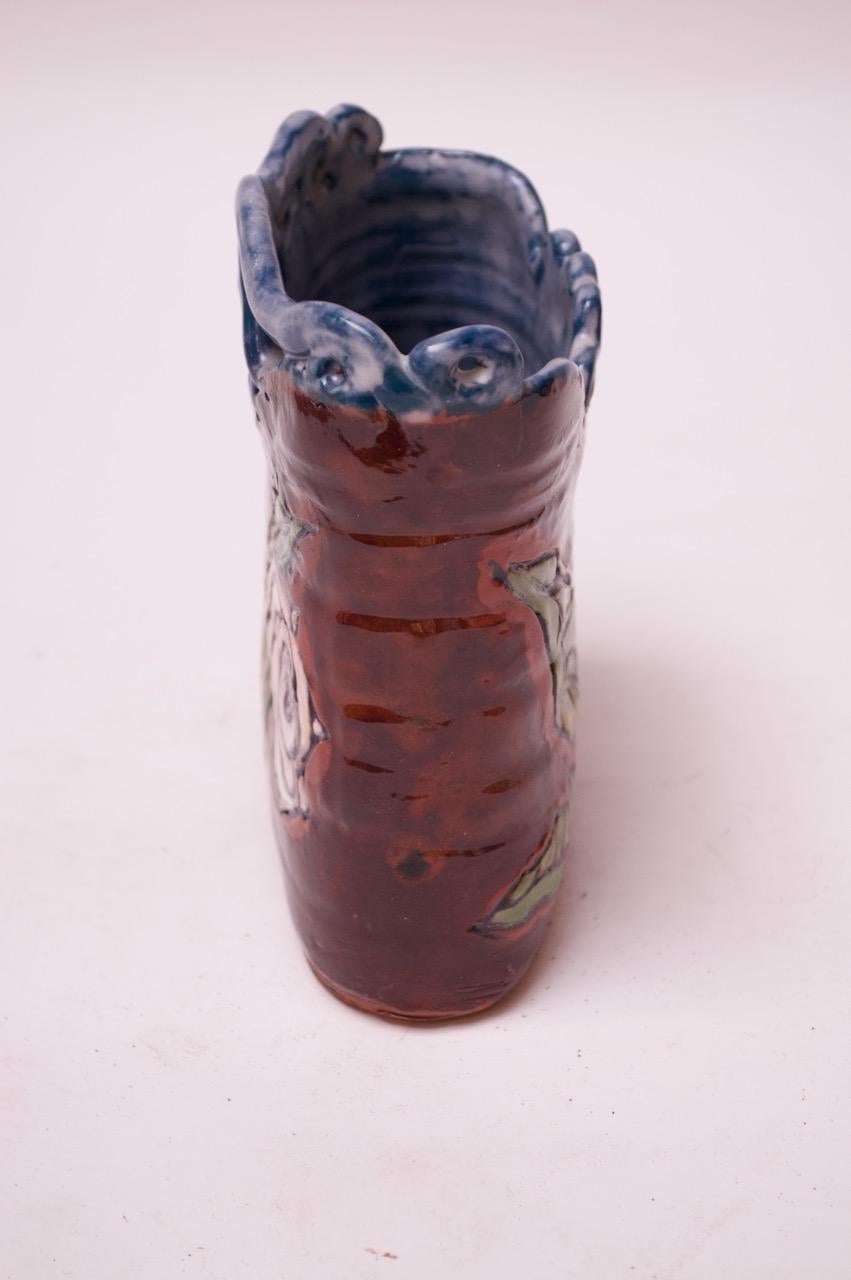 Terrakotta-Vase aus den USA mit beidseitigem Blumenmotiv in einer hochglänzenden Glasur aus Rot, Blau, Weißgrün und Gelb, um die Mitte des 20. Jahrhunderts.
Auf der Unterseite signiert 