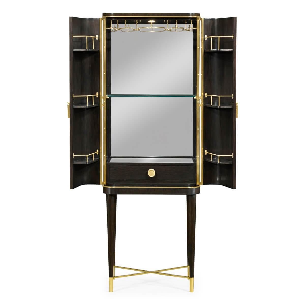 A midcentury style two-door bar cabinet with chinoiserie decorated etched brass doors, a fitted mirror back interior with a glass shelf, glass racks, storage shelves, and single drawer raised on tapered leg base having brass feet and an 'X'