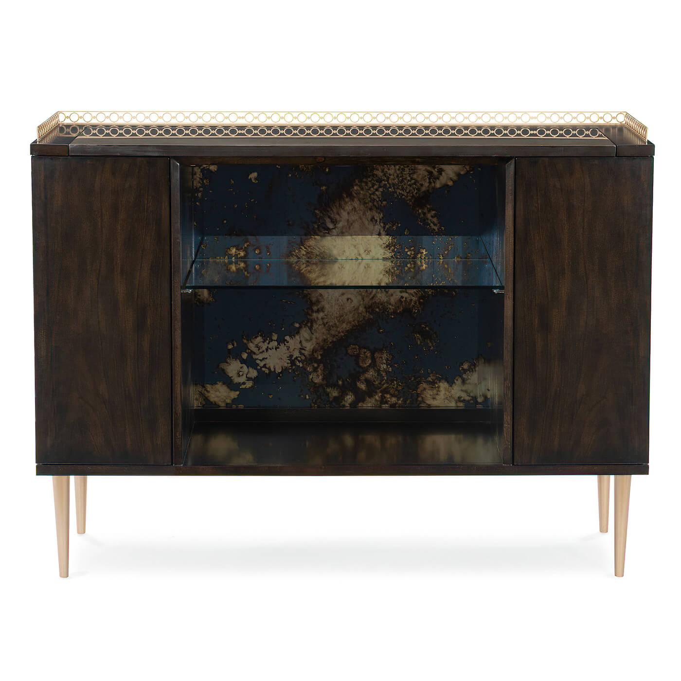 A mid-century-style bronzed ebony bar cabinet with a Koris Coffee Stone top outlined with a pierced metal gallery finished in Warm Silver Metallic paint. An open center section reveals an antiqued mirrored back and glass shelf illuminated by a touch