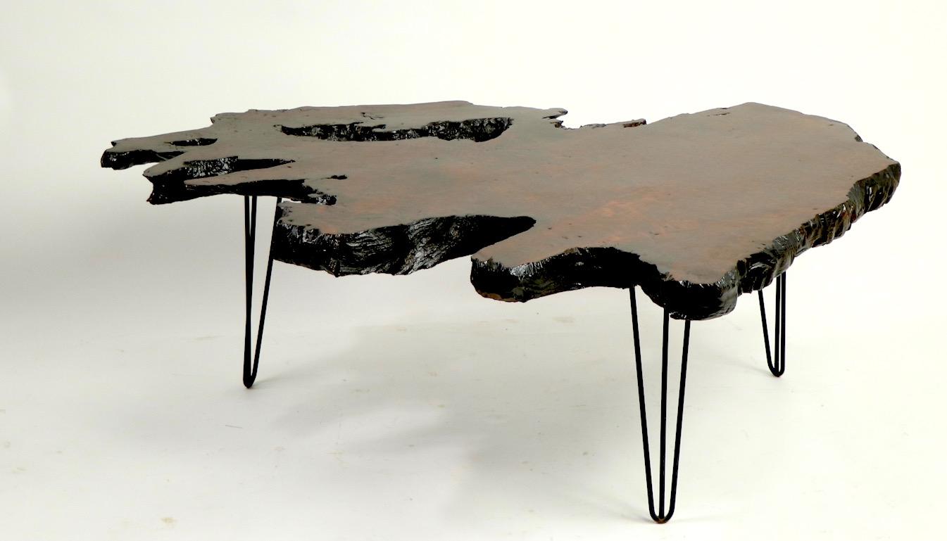 Organic free edge coffee table having a solid rosewood top, and three, three prong tapering wrought iron legs.
 