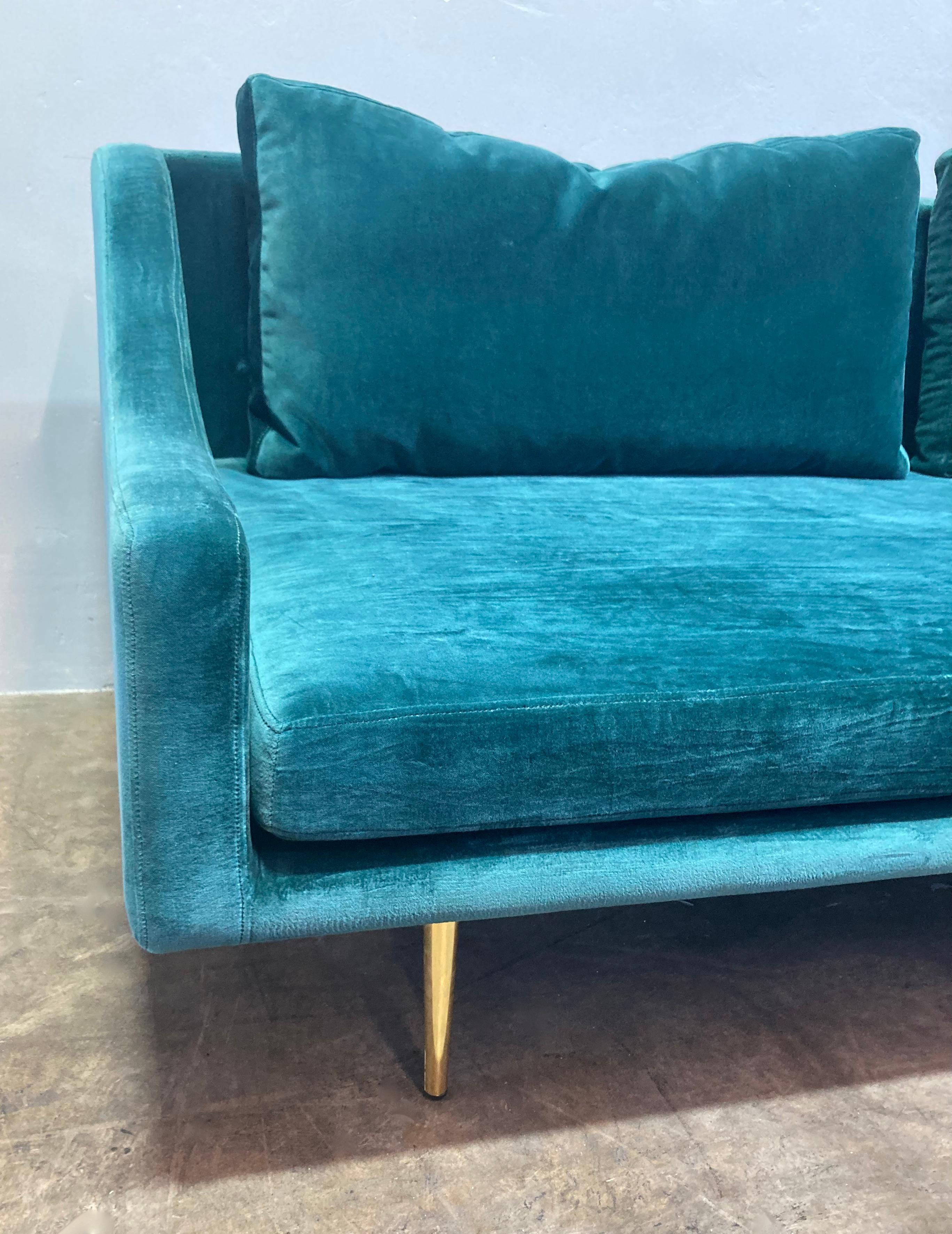 Contemporary manufacture with mid-century flair. Elegant and practical sofa, upholstered in green velvet with gold-toned hardware. Wider than your average loveseat, seating 2-3 comfortably. Fits perfectly with a range of aesthetic styles, including