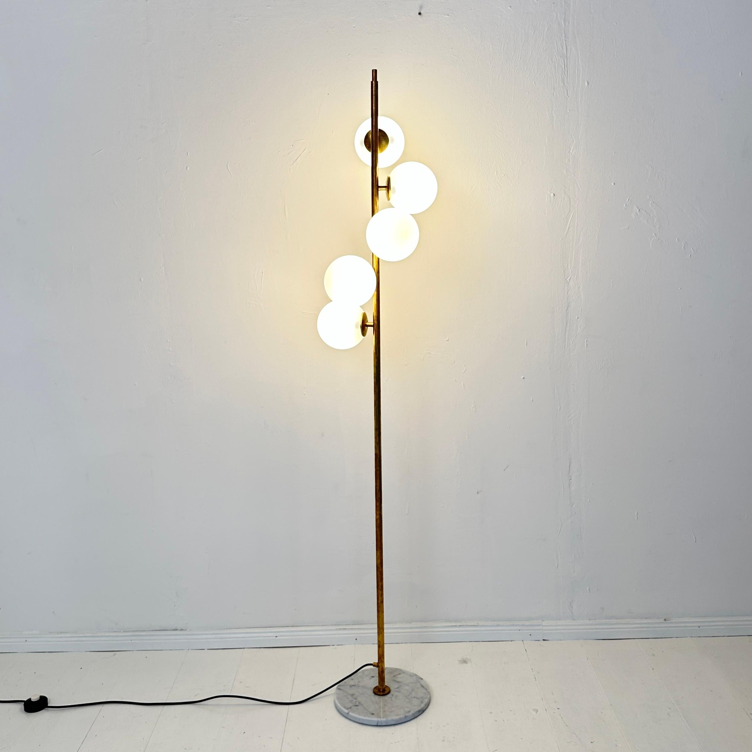 
Ce lampadaire italien de style milieu de siècle respire l'élégance et la sophistication, fabriqué avec une combinaison raffinée de laiton, de marbre et de verre opalin. Le design de la lampe se caractérise par une tige élancée en laiton ancrée par