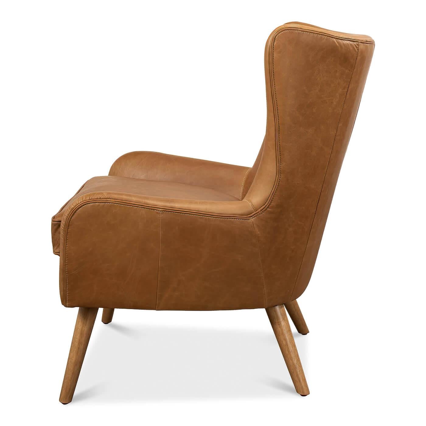 A Mid-Century Modern style brown leather armchair. The top and the arms of the chair feature a smooth curved design and sits on splayed hardwood framed legs. The back of the chair has tailored tufted button accents. This contemporary chair has a nod