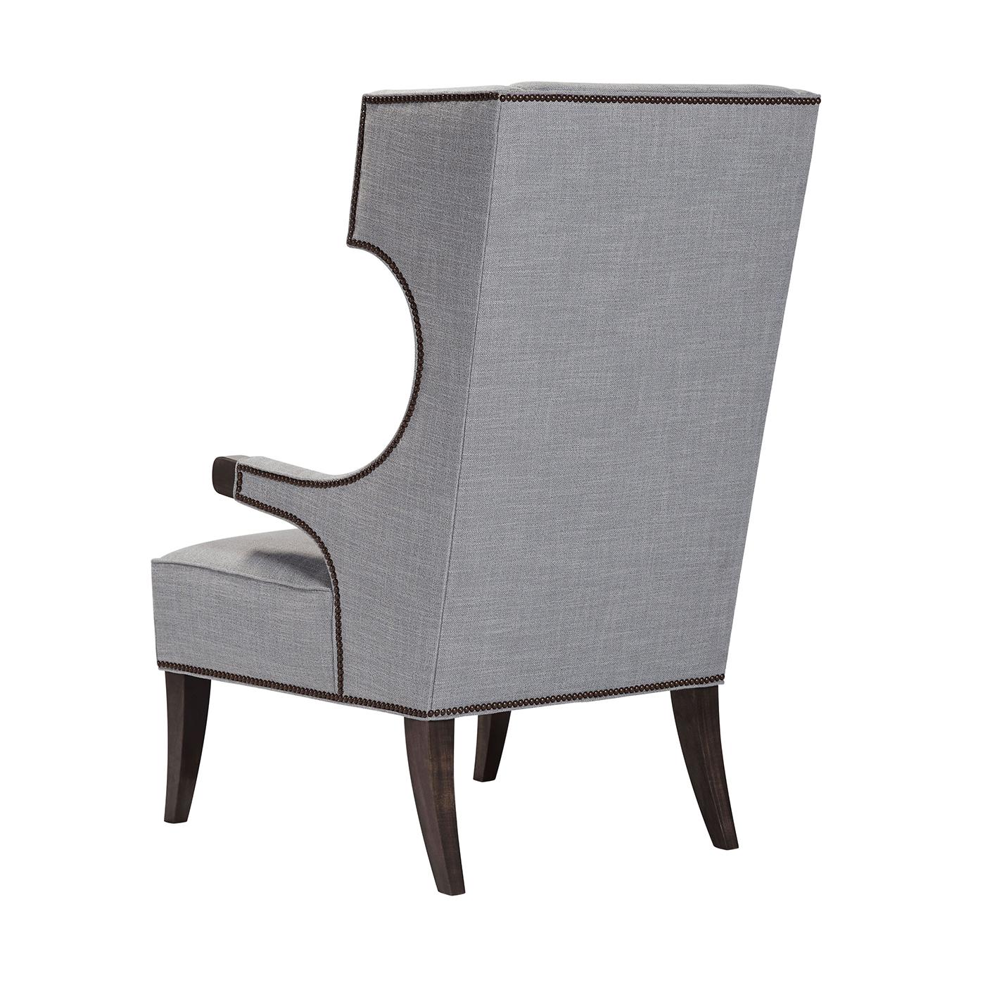 A midcentury style wingchair with an upholstered cushion, a tight angled winged backrest with down swept arms and exposed show wood ends, on tapered sabre legs and finished with nailhead trim details.
Dimensions: 31