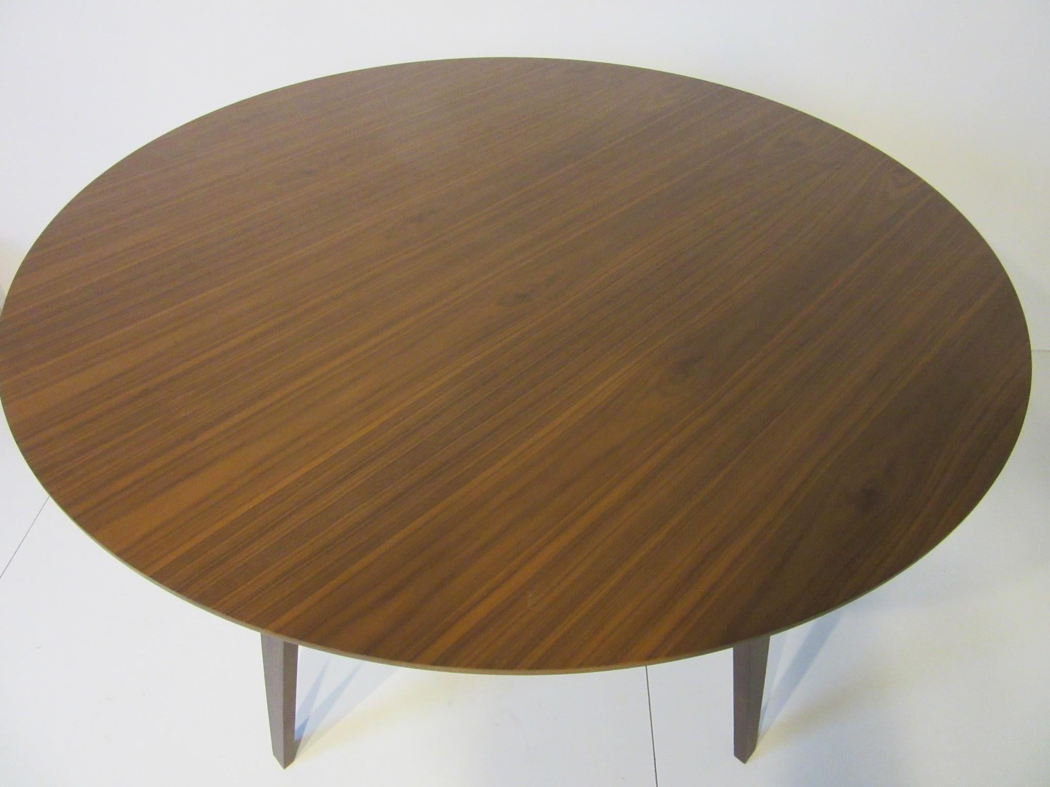 A round walnut dining table with matching tapered bent wood legs in the manner of the iconic Cherner chair designed by Norman Cherner. This table is manufactured and retains the label by the Cherner Chair Company and designed by Benjamin Cherner