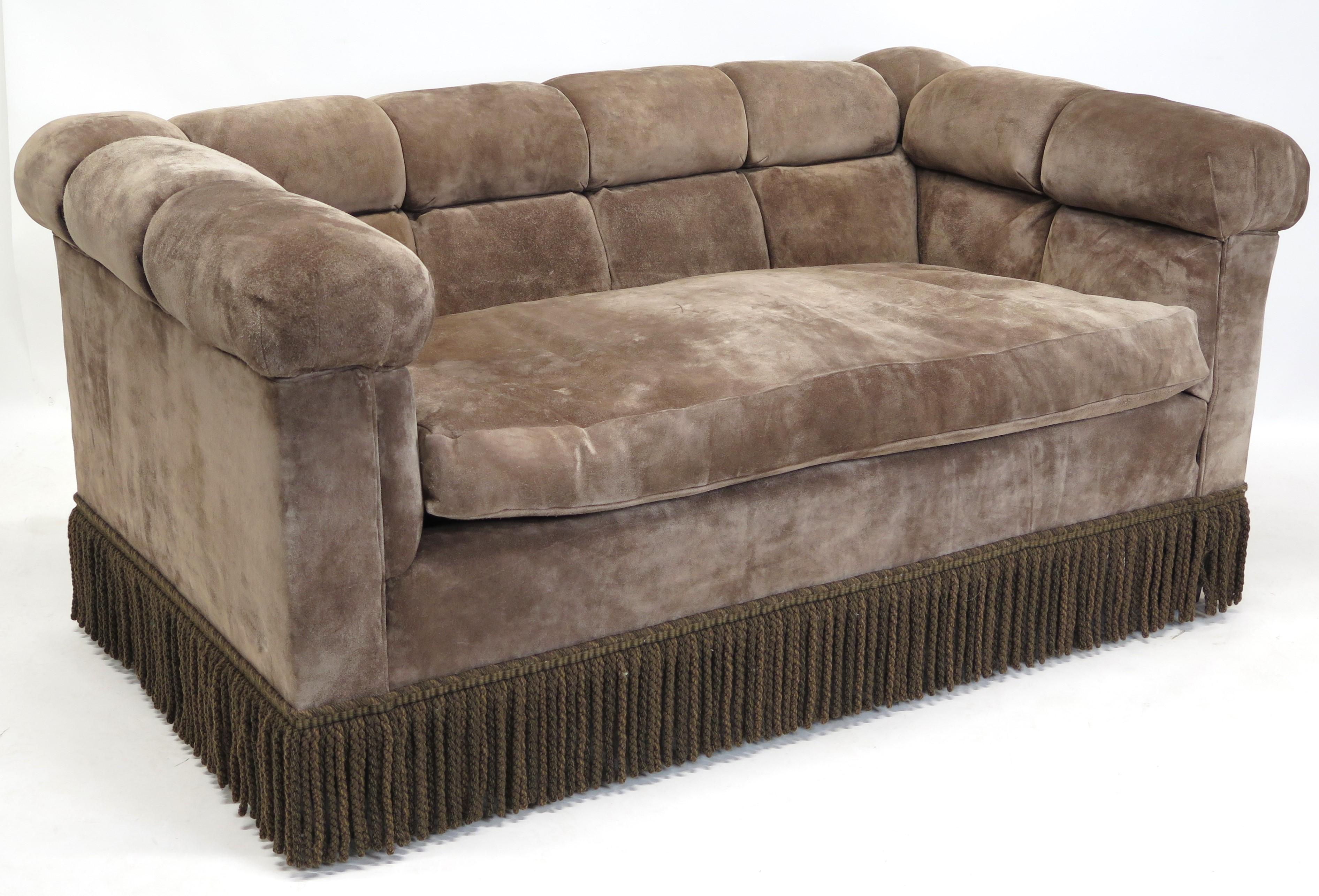 mid-century modern Dunbar Chesterfield sofa with brown suede button tufted upholstery and bullion fringe, single seat cushion, early 1960s 

the sofas, originally low to the floor, were raised as their owner got older, the bullion fringe was added