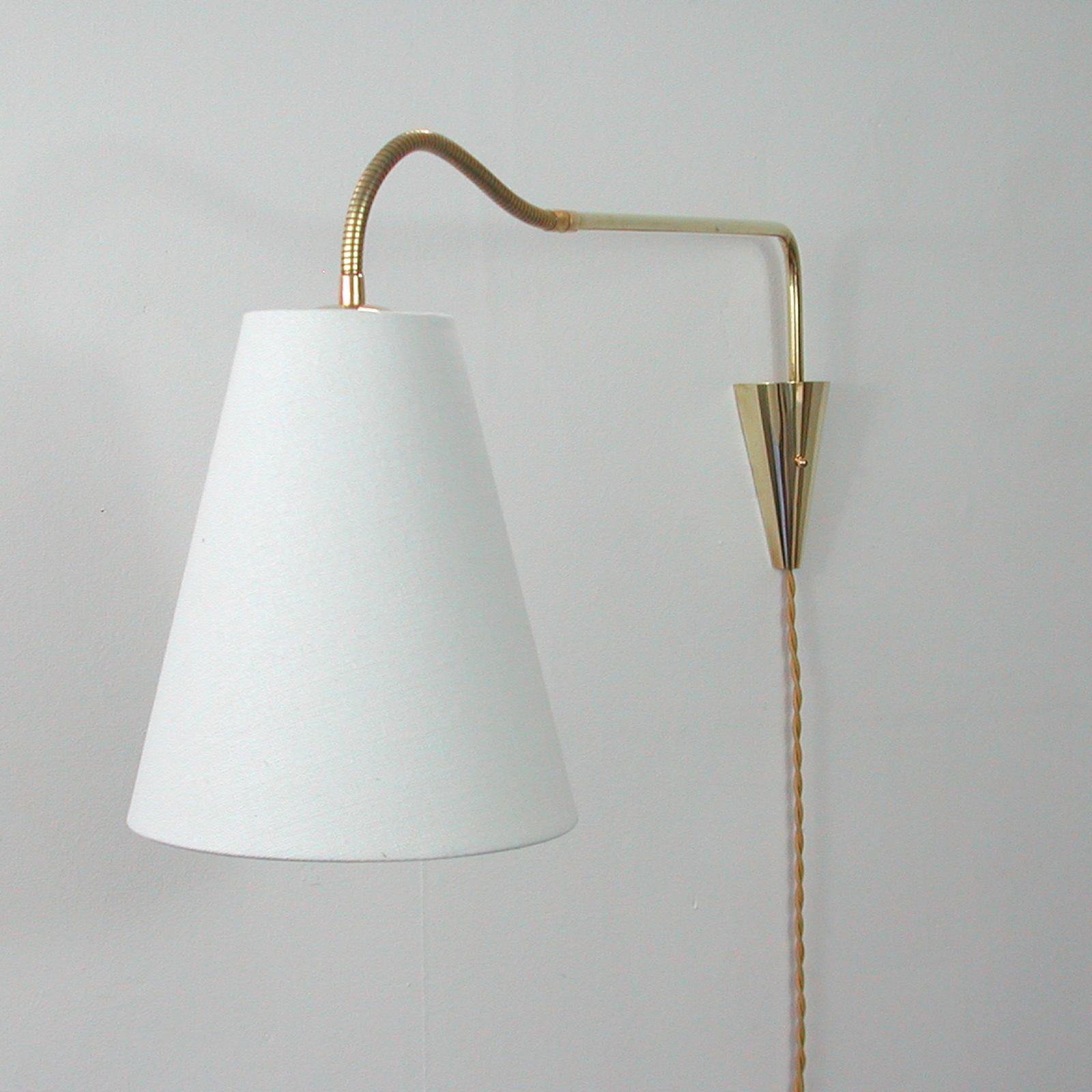 This unusual articulating and adjustable wall light was designed and manufactured in Sweden in the 1950s. The light features brass hardware and a new off-white fabric (linen) lampshade. It requires one E27 bulb. Wired with new silk cord for use in