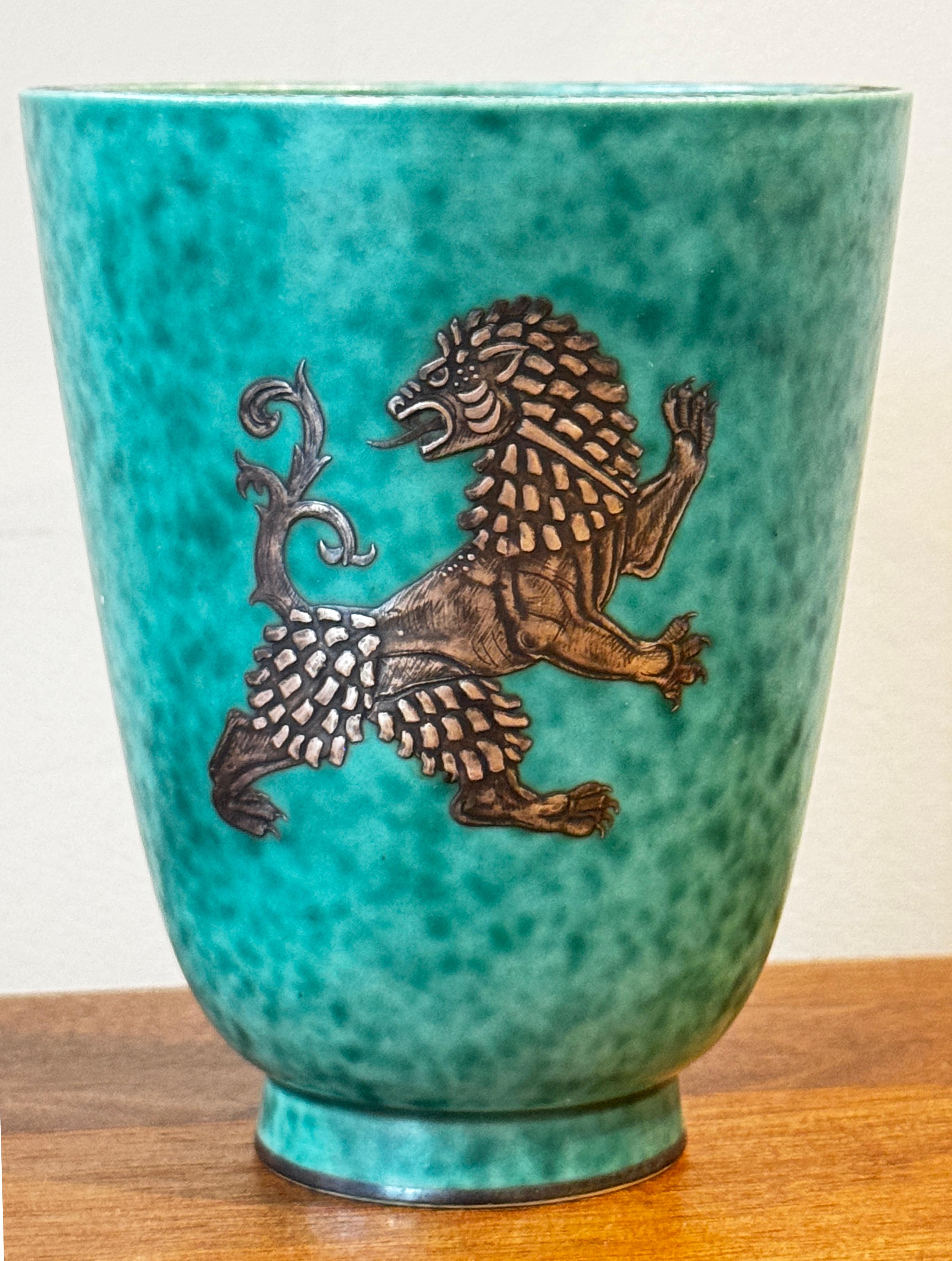 Este jarrón clásico de la modernidad escandinava pertenece a la serie Argenta, diseñada por Wilhelm Kåge para Gustavsberg. Precioso ejemplo de la gracia sueca y del diseño de mediados de siglo, el jarrón está decorado en plata sobredorada con una