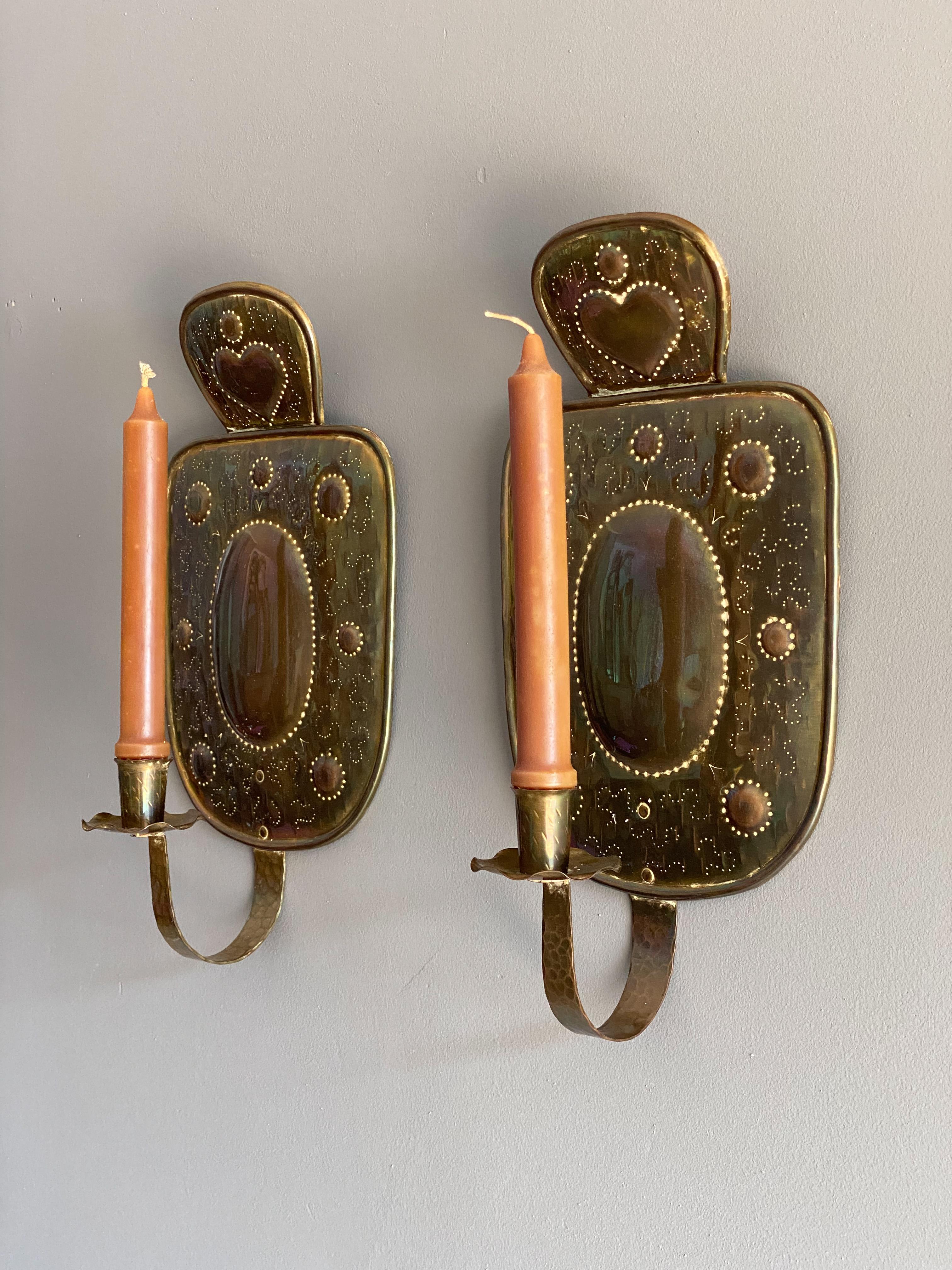 A pair of lovely Swedish country style sconces. Executed in tooled solid brass with embossed styling and hearts. Each is hand hammered and shows a wonderful patina. Would be an excellent choice for Scandinavian or farm house setting. Would also look