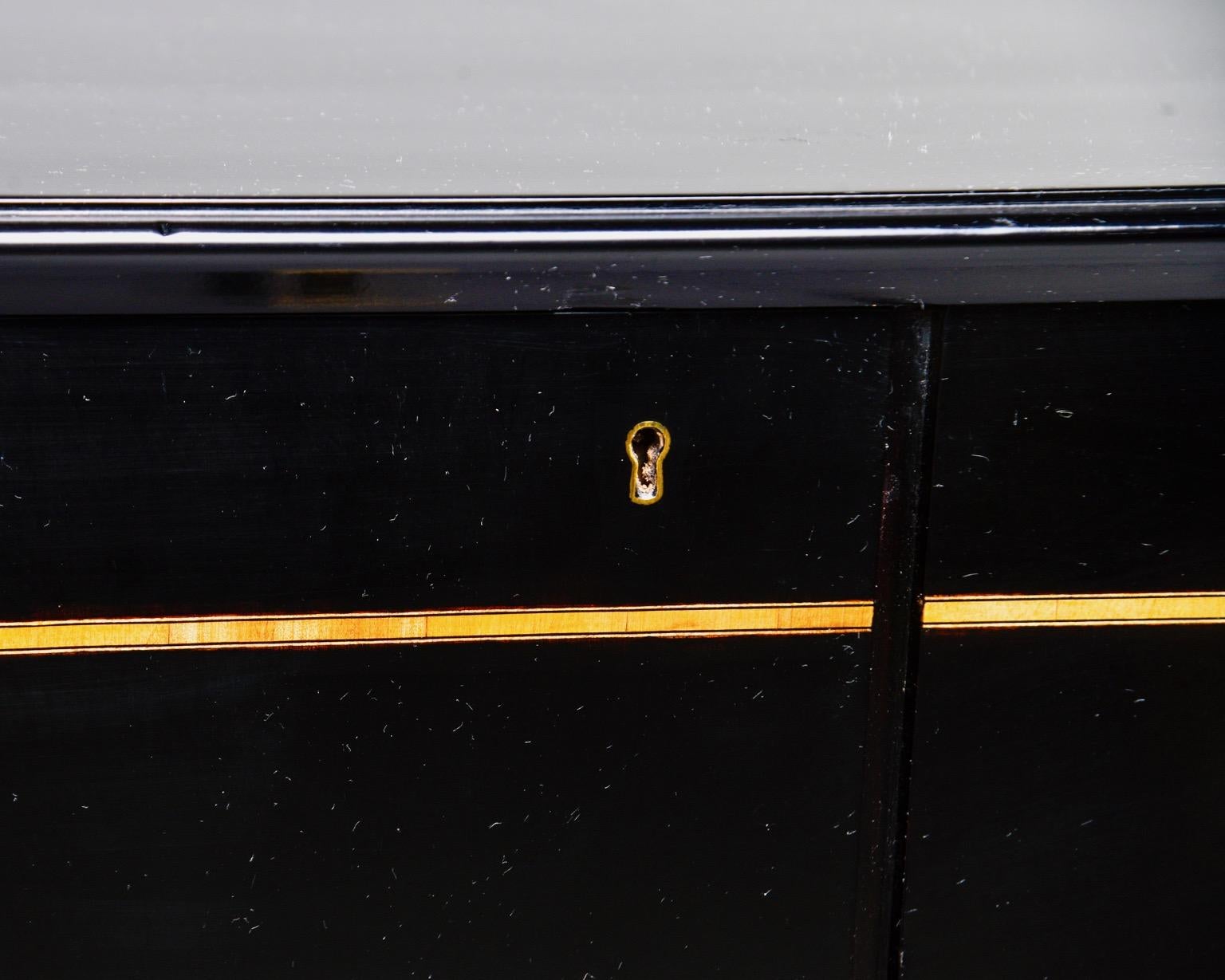 Two-door Swedish cabinet has a new, professionally applied ebonized finish and two hinged doors, circa 1950s. Inside, one side features two internal shelves while the other side has two functional drawers and a shelf. New brass handles accentuate