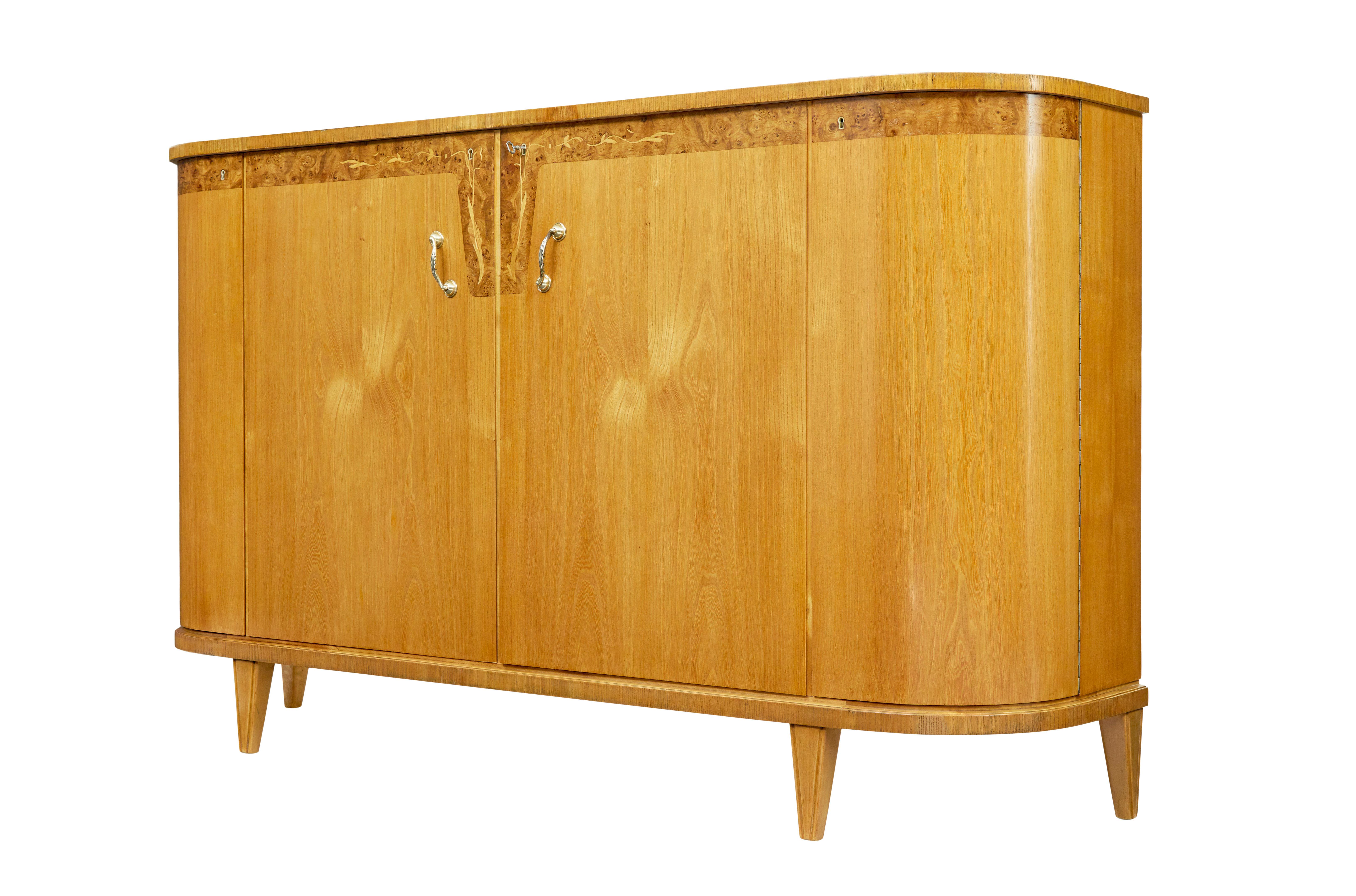 Mid century Swedish inlaid elm sideboard circa 1940.

Swedish sideboard very much in the art deco taste.  High board with rounded ends, veneered in elm.

Below the top surface the piece is decorated with a burr walnut border, finished with inlaid