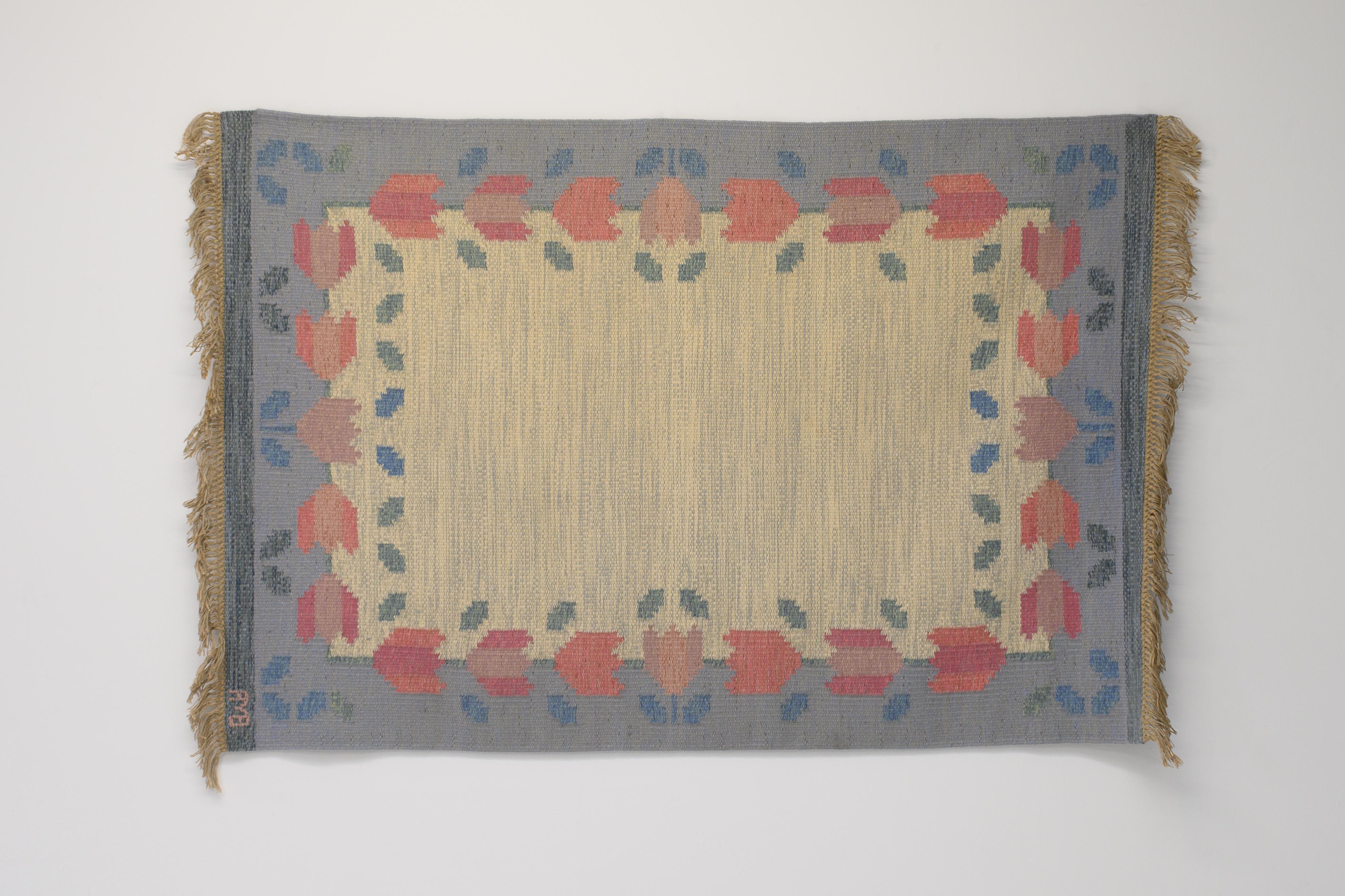 Mid-Century Swedish floral kilim by Anne Marie Boberg, in tones of blue and cream with a tulip pattern border. Signed. Professionally cleaned.