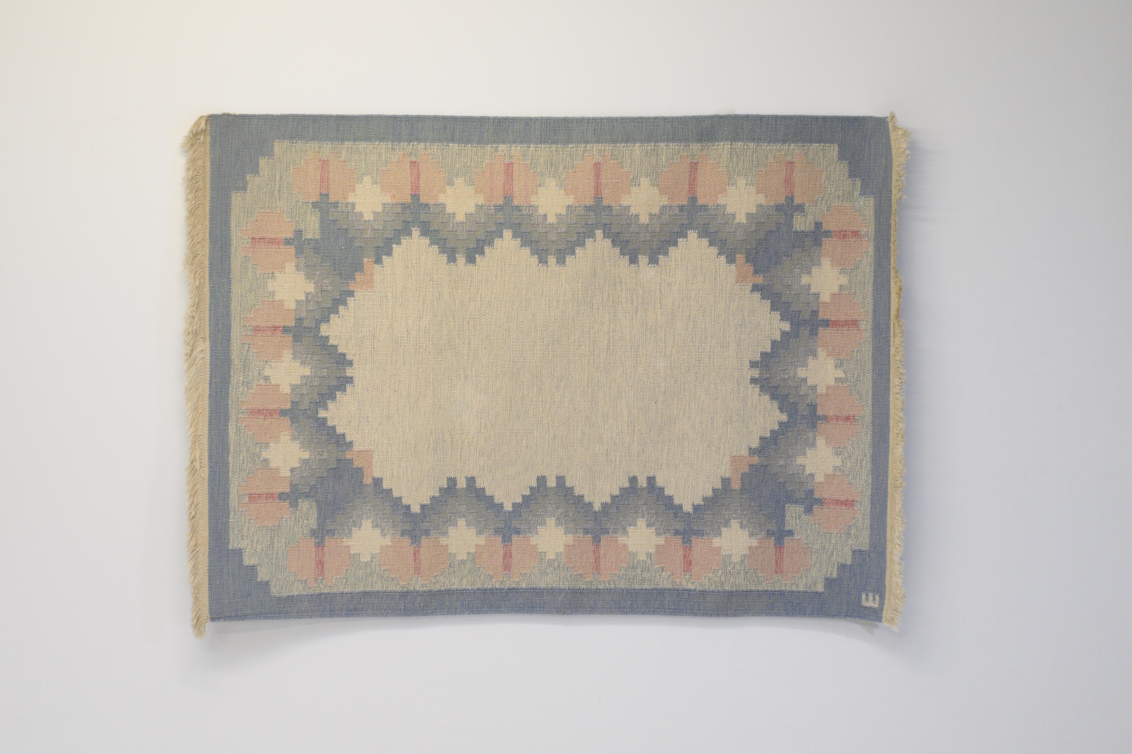 Mid-Century Swedish Kilim in tones of blues and creams, with a zig-zag border including pinks surrounding a cream central area. Professionally cleaned. Signed E.