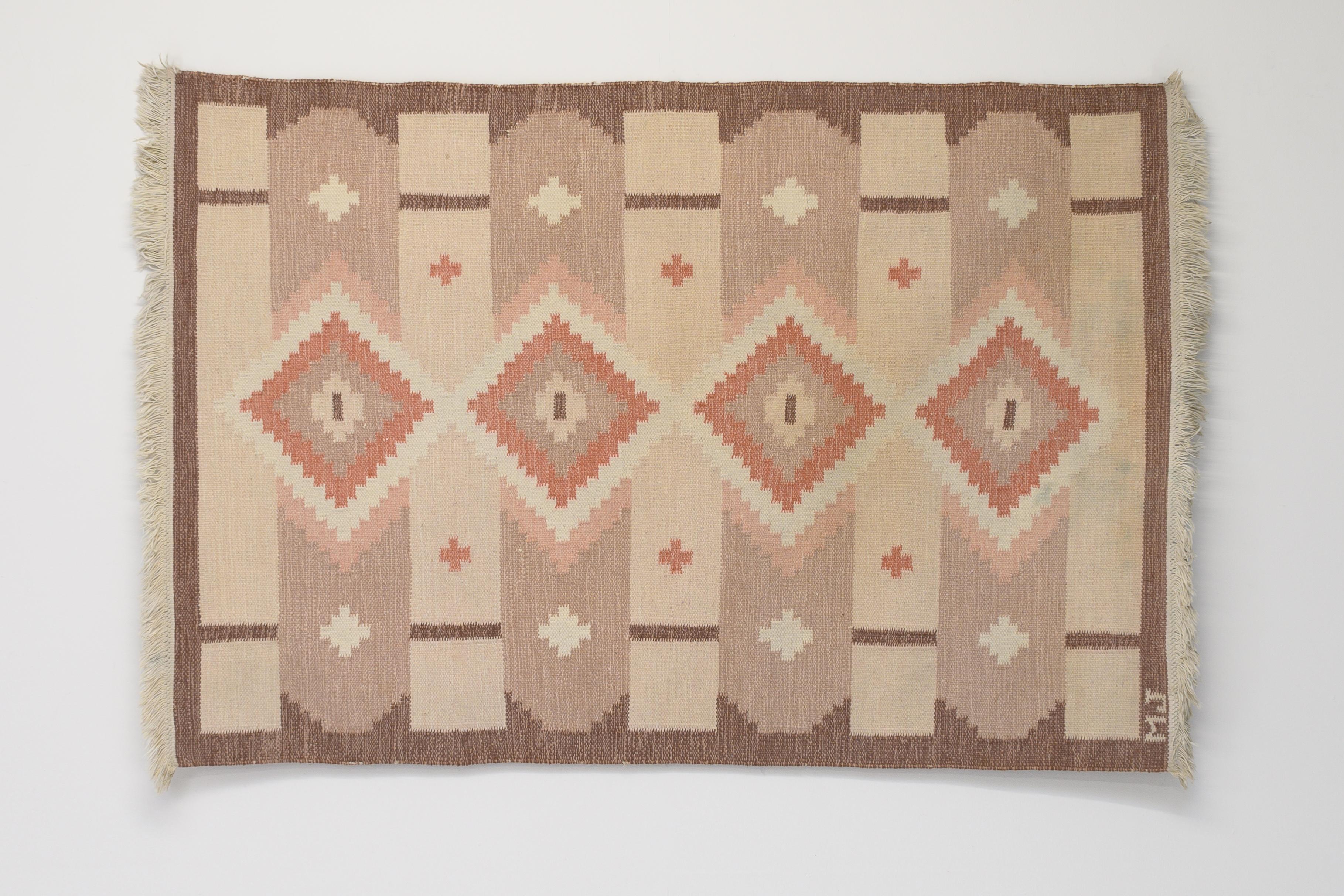 Swedish Kilim in tones of brown and pink. Great geometric pattern with pink diamonds running down the centre. Signed MJ. Professionally cleaned.