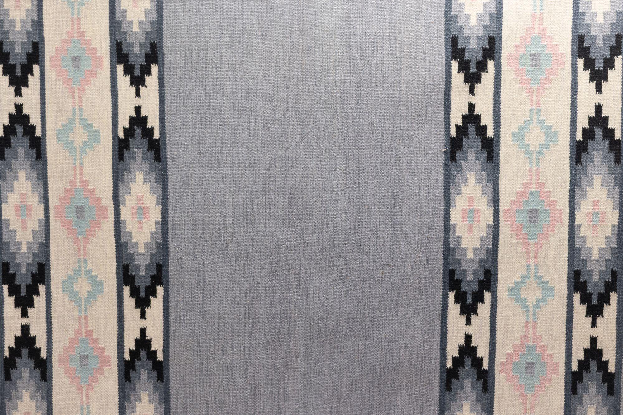 Schwedischer Kelim aus der Jahrhundertmitte in Grautönen mit einem einfarbigen Mittelmotiv und geometrisch gemusterten Fransen. Schweden um 1960. Alle unsere Teppiche werden einer professionellen Reinigung unterzogen. Aufgrund ihres Alters und ihres