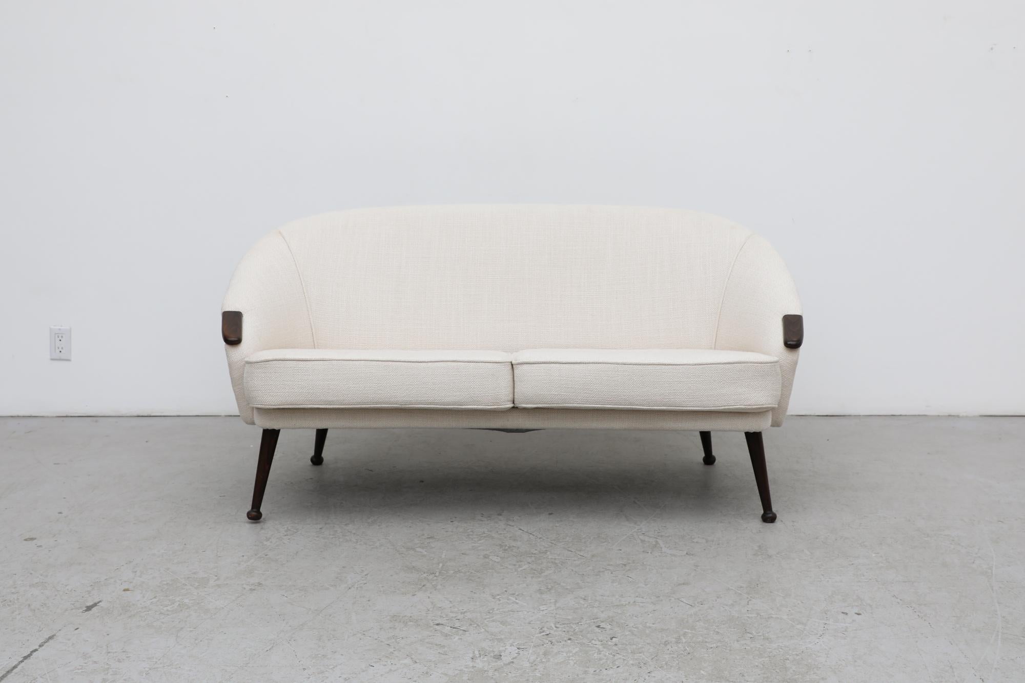 Swedish cream white loveseat sofa with tapered legs and wood details on the arms. Legs are tapered with a carved ball on the end. Slightly uneven, but sit flat when seated in the loveseat. The upholstery has beed recently re-done by previous owner,