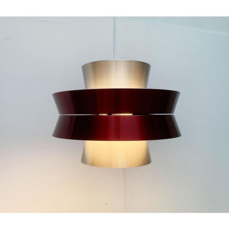 Pendant lamp from Swedish manufacturer Granhaga based on a design by Carl Thore.

A distinctive detail of Thore's designs is the staggered slats with outward sloping angles. These are mirrored across the central axis, creating an asymmetrical body.