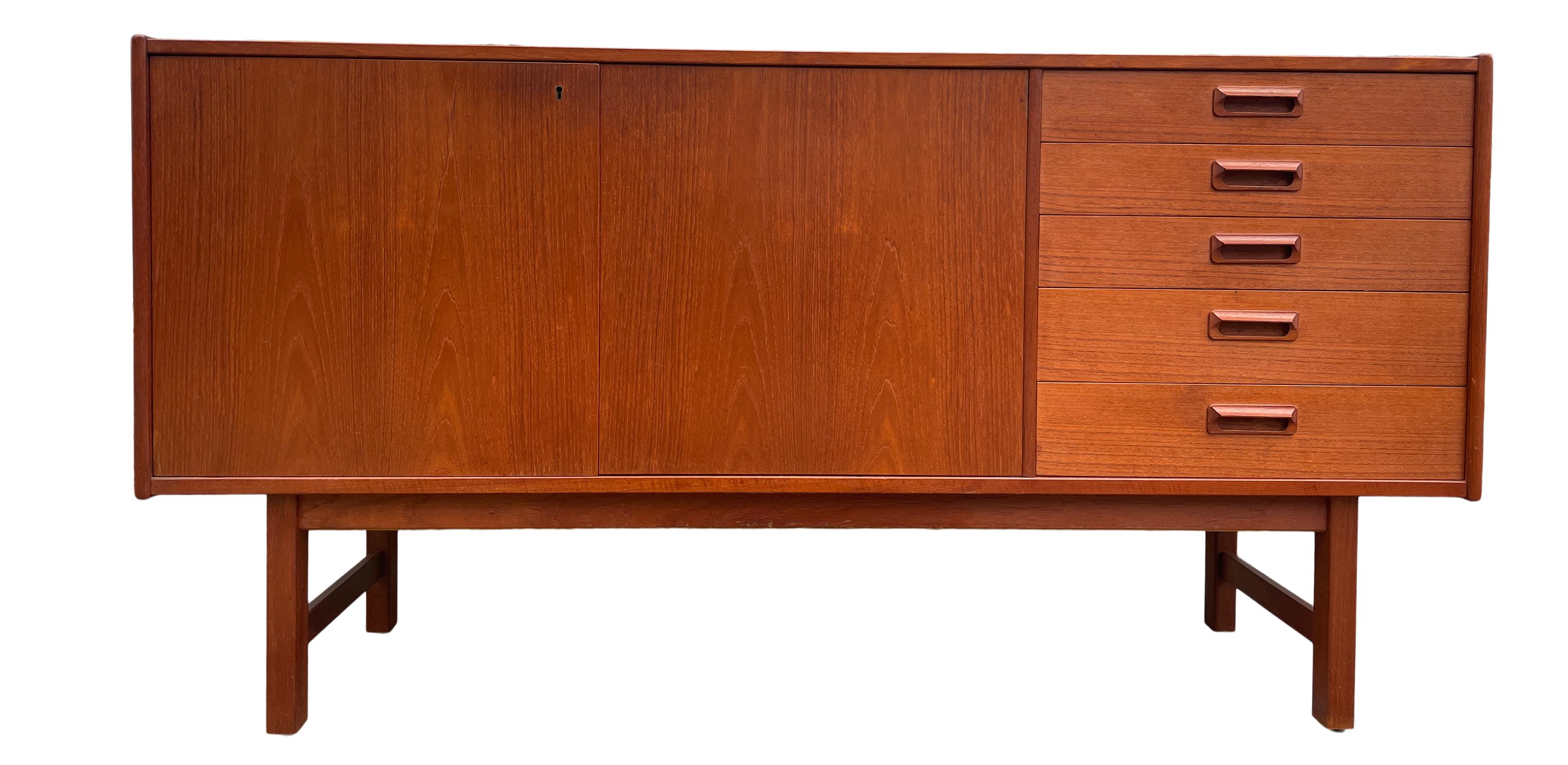 Mid century Swedish modern 5 drawer teak credenza with locking cabinet doors. beautiful teak sideboard - with 5 drawers - top drawer is felted with sections for flatware. Cabinet doors open to (1) long adjustable shelf with locking doors (1)
