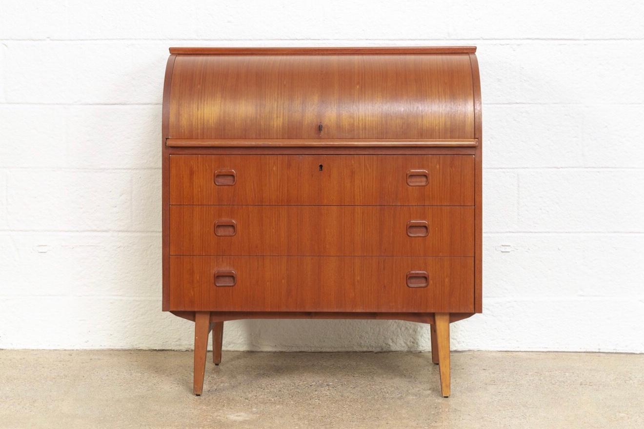This iconic midcentury Swedish modern Egon Ostergaard teak cylinder rolltop secretary desk cabinet is circa 1970. The Classic Scandinavian Modern design has clean Minimalist lines. The rolltop opens on to a top compartment with small drawers and
