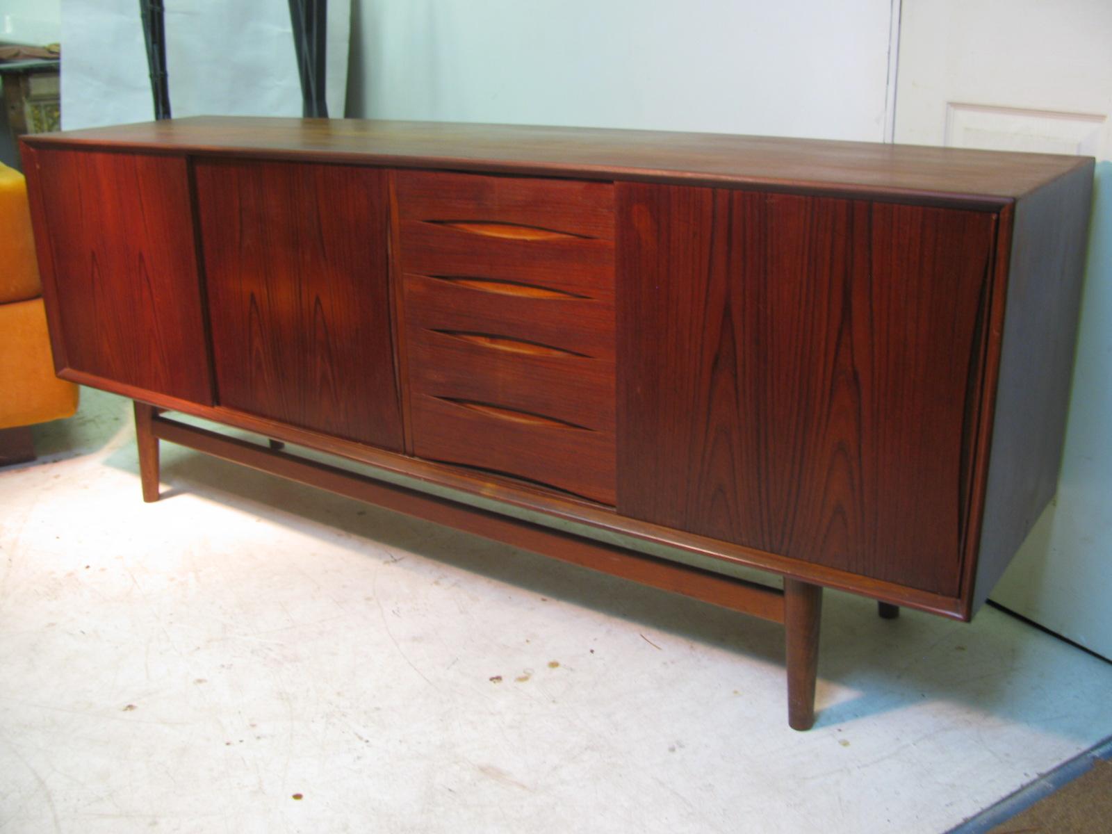 Beautiful vintage teak credenza with a rich and deep patina that has mellowed over the years. Three sliding doors which reveal a large and a small shelf along with five graduated drawers also for storage. Finger slots on all doors and drawers