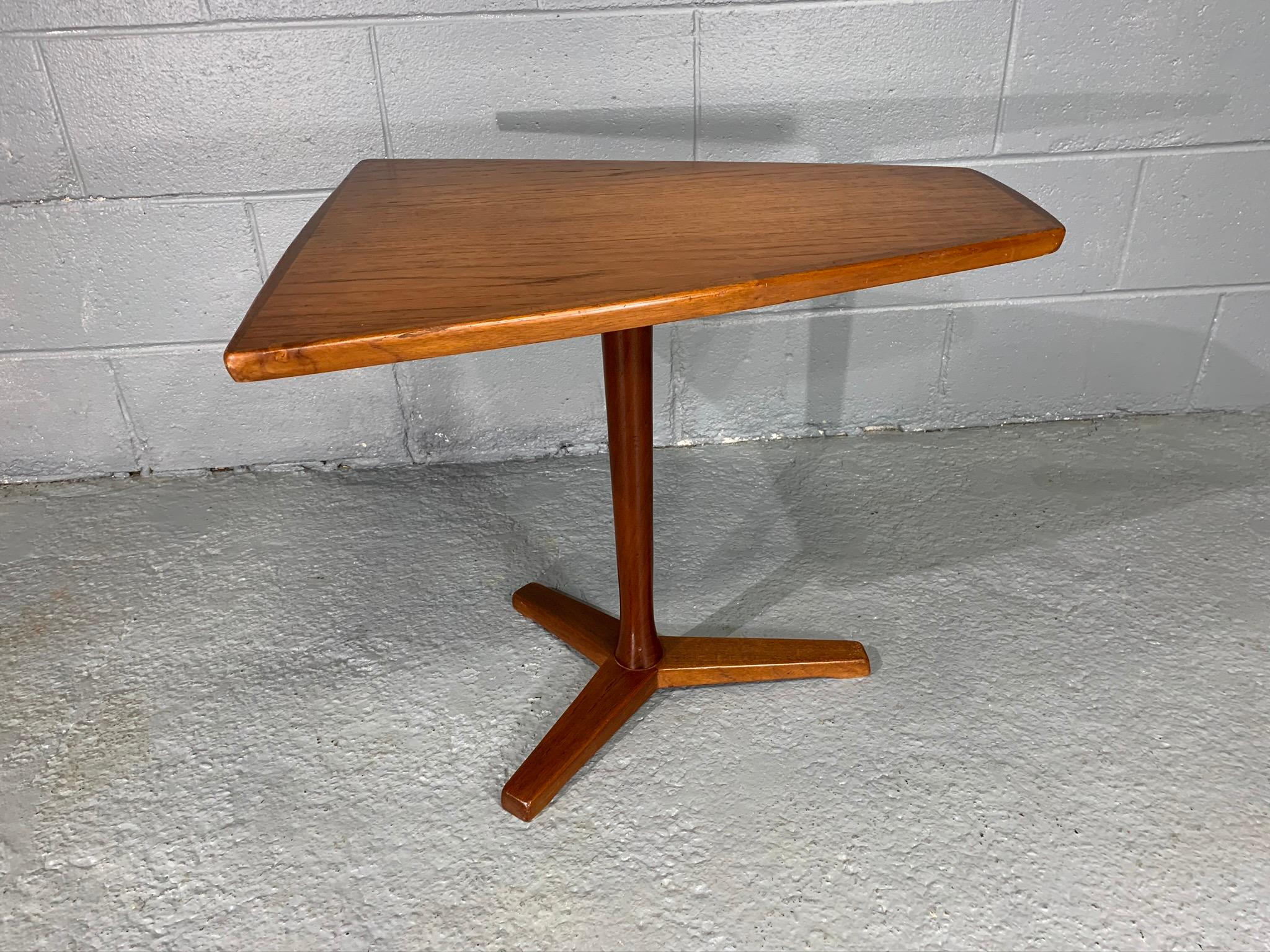 Unique side table with geometric, trapezoidal top manufactured by DUX of Sweden, circa 1960s. This teak tri-leg table plays with shapes and sizing creating a Minimalist Scandinavian Modern aesthetic. Top width starts at 20 inches and narrows to 8