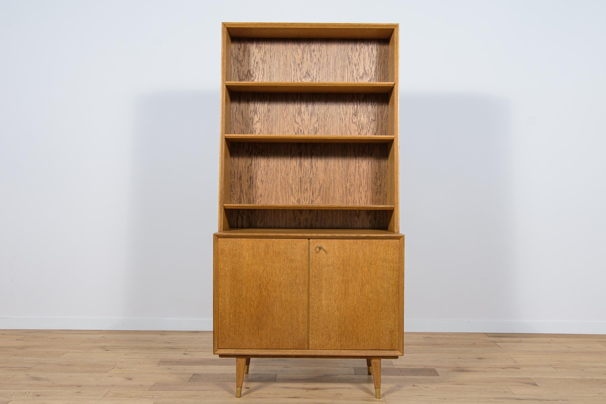 
This mid century shelf in oak was manufactured in the Sweden the 1970s. In the upper part there are four open shelves, in the lower part there is a cabinet with two shelves and two drawers. The furniture has metal leg fittings that have been