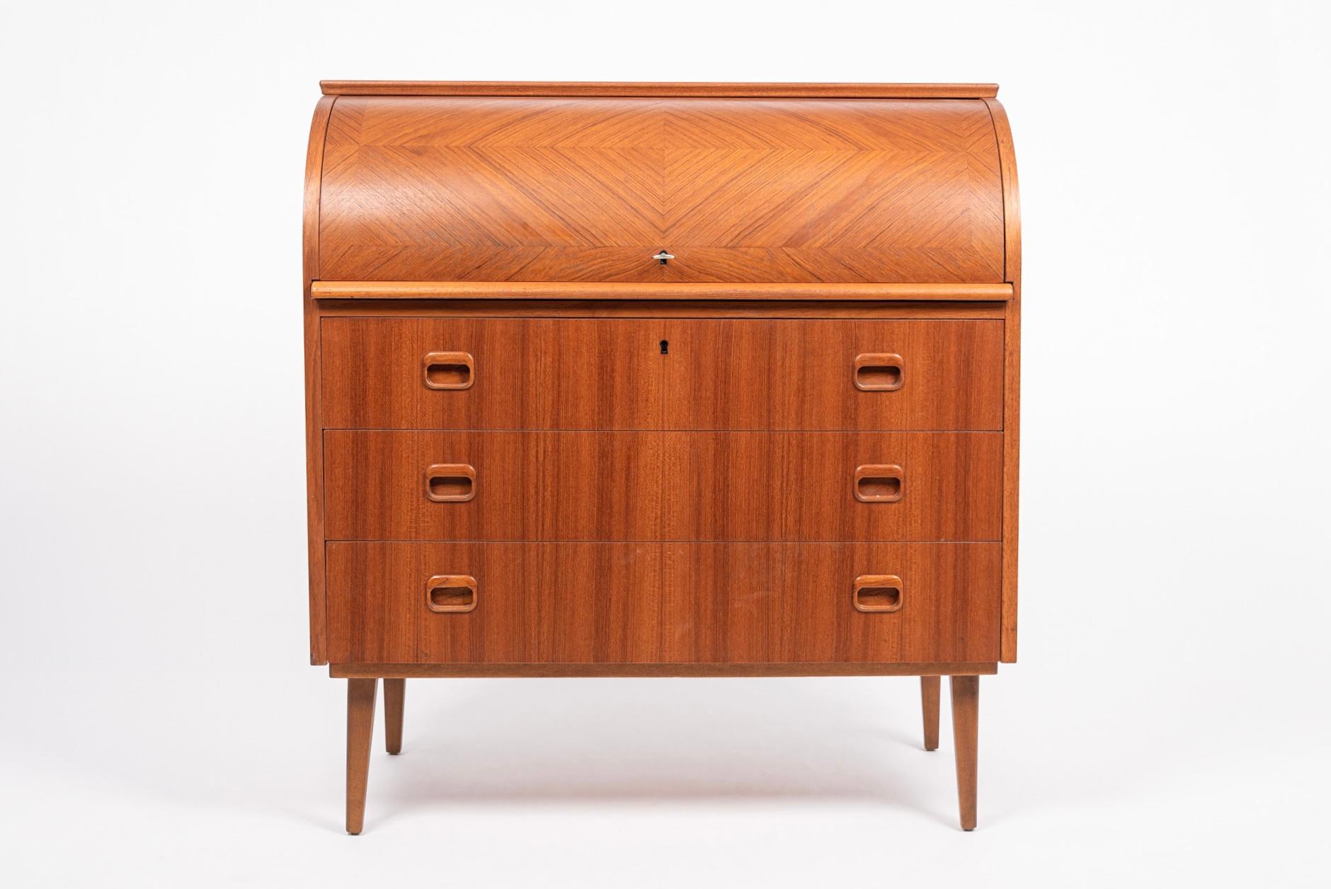 This iconic vintage midcentury Swedish modern Egon Ostergaard teak cylinder rolltop secretary desk cabinet was made in Sweden circa 1960. The Classic Scandinavian Modern design has clean, Minimalist lines and gentle curves. The teak wood finish is a