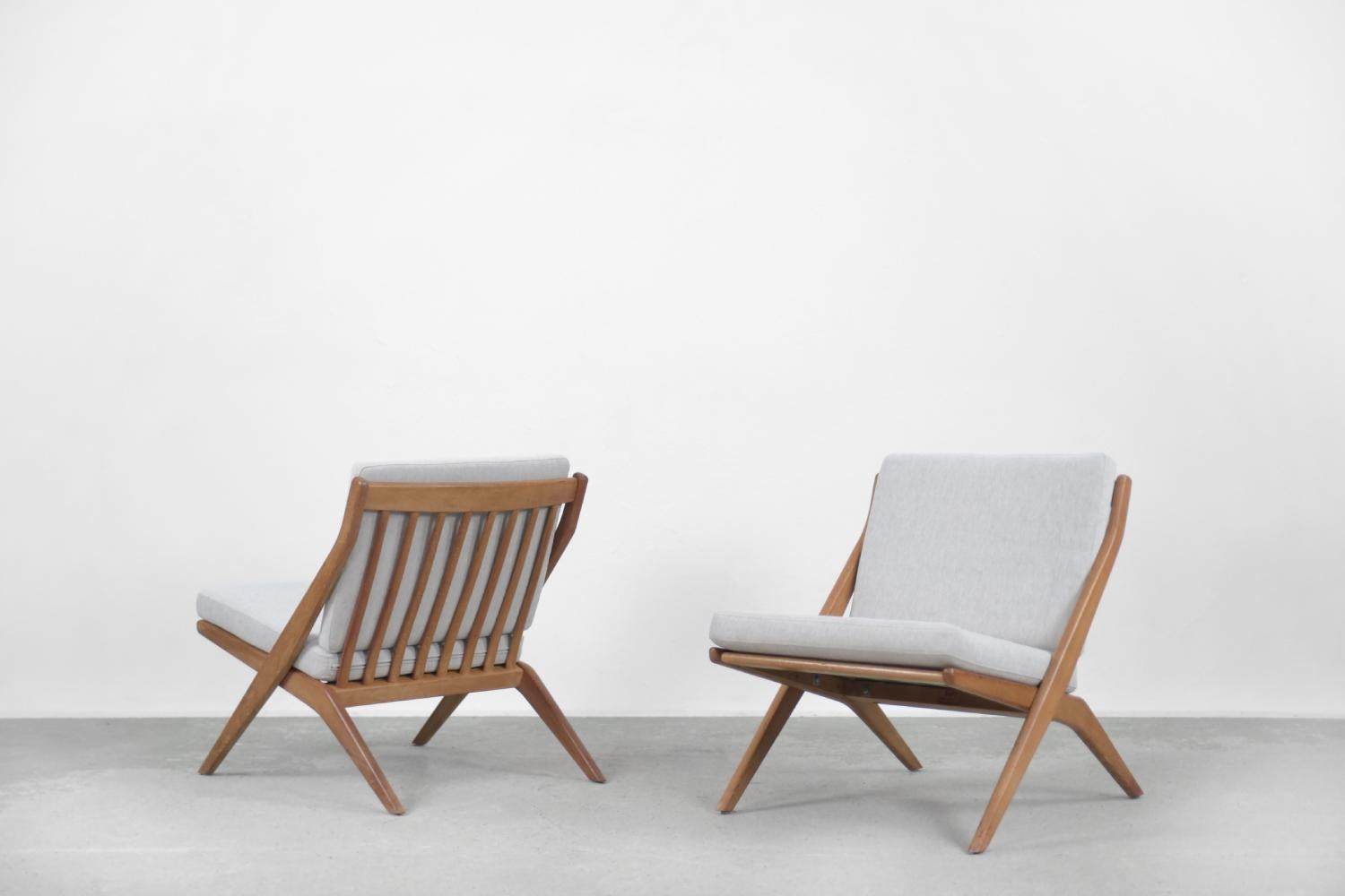 This Scissors armchair set of two was designed by Folke Ohlsson for the Swedish manufacturer Bodafors in 1962. It has a scissor oak frame with eight slats on the backrest. The loose cushions have been re-upholstered in a high-quality gray textured