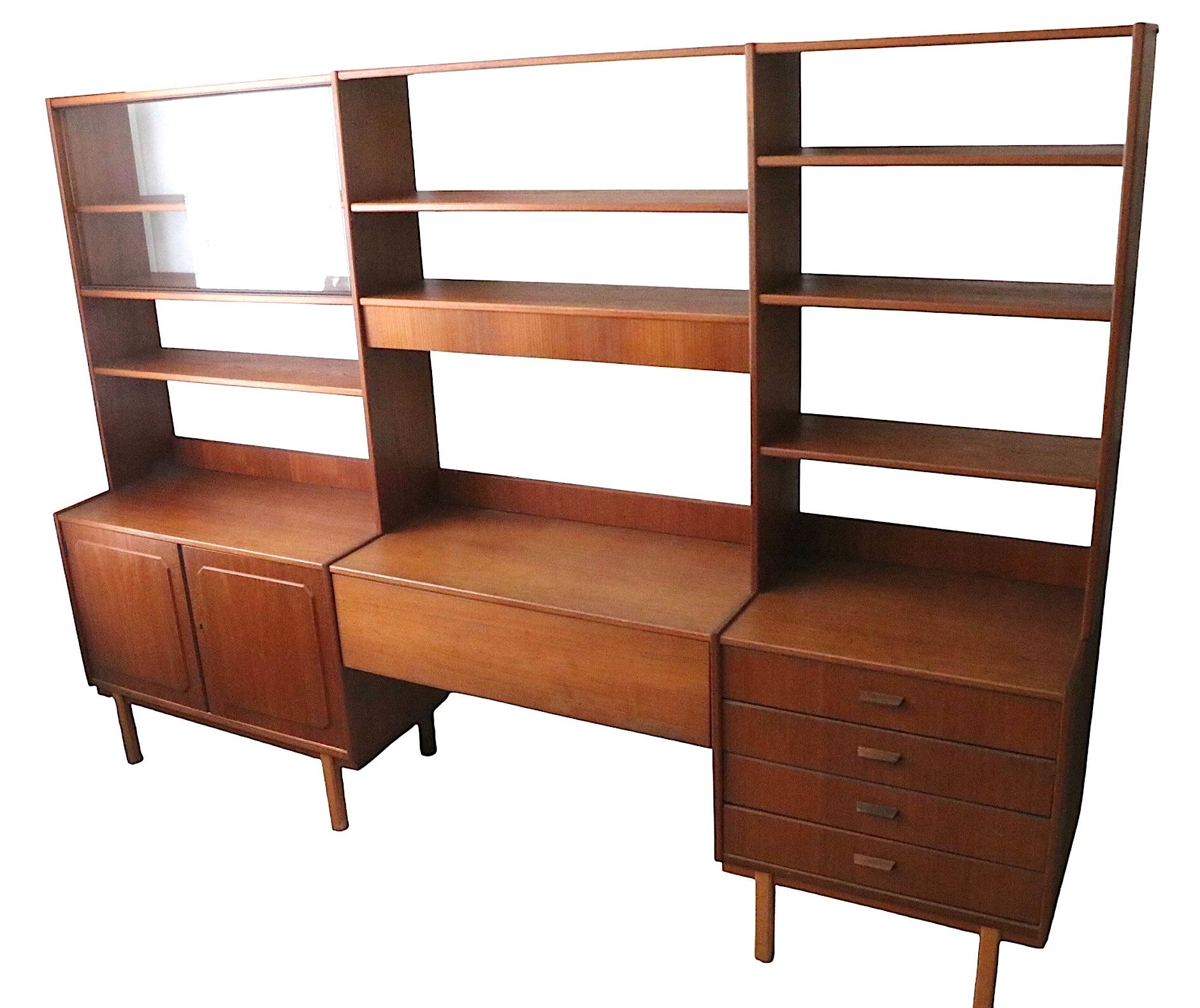 Pensile, mensole e scrivania del Mid Century Modern scandinavo, disegnato da Bertil Fridhagen per Bodafors, intorno agli anni 1950/60. Questo pezzo presenta tre campate,  uno con una vetrina con ante scorrevoli, un ripiano regolabile e un mobile a