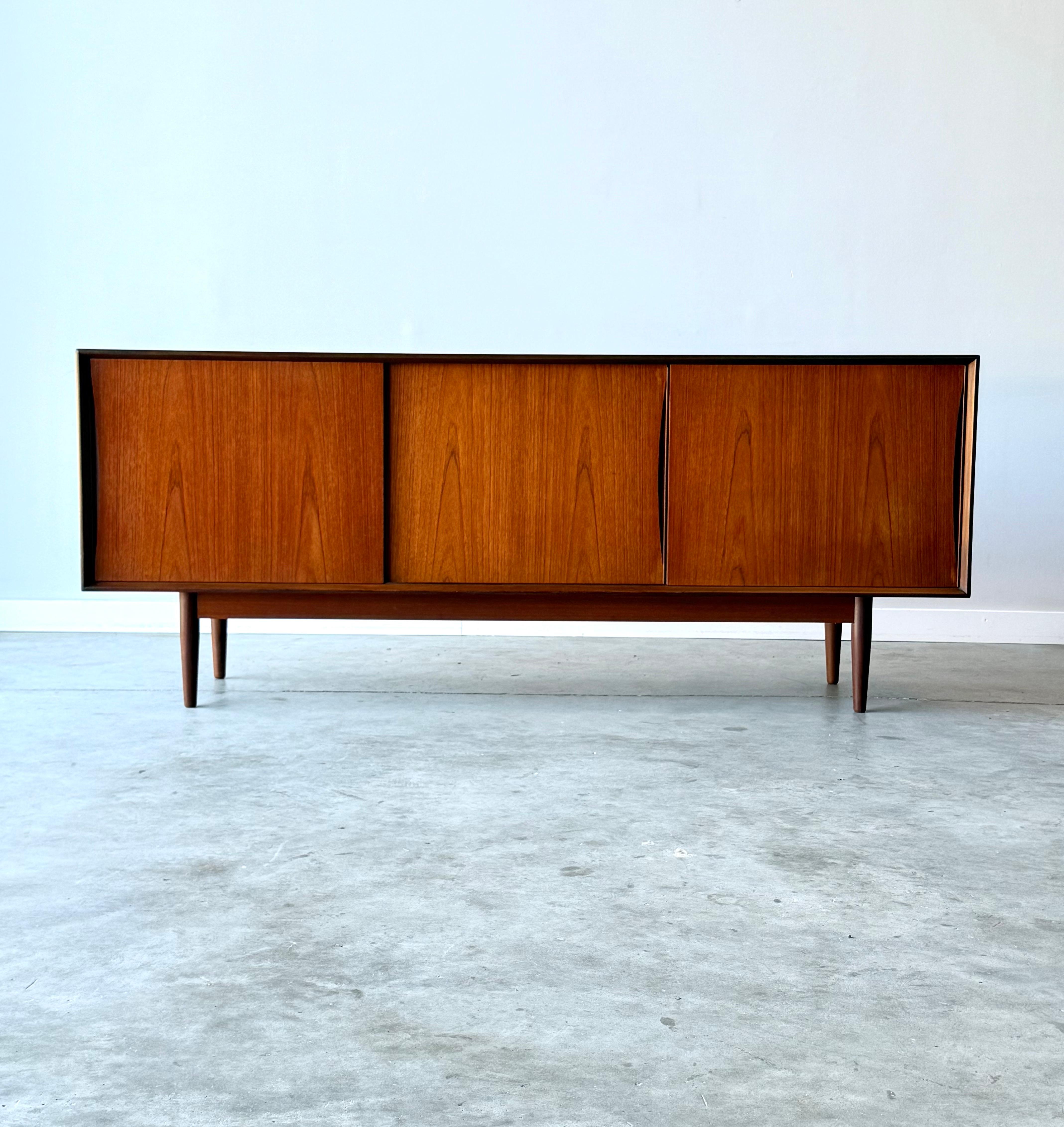Credenza svedese di metà secolo, realizzata intorno agli anni '60. Questo pezzo è realizzato in legno di teak e poggia su gambe affusolate in teak. Dotato di tre porte scorrevoli. Ogni porta è dotata di un'elegante maniglia intagliata che la mette