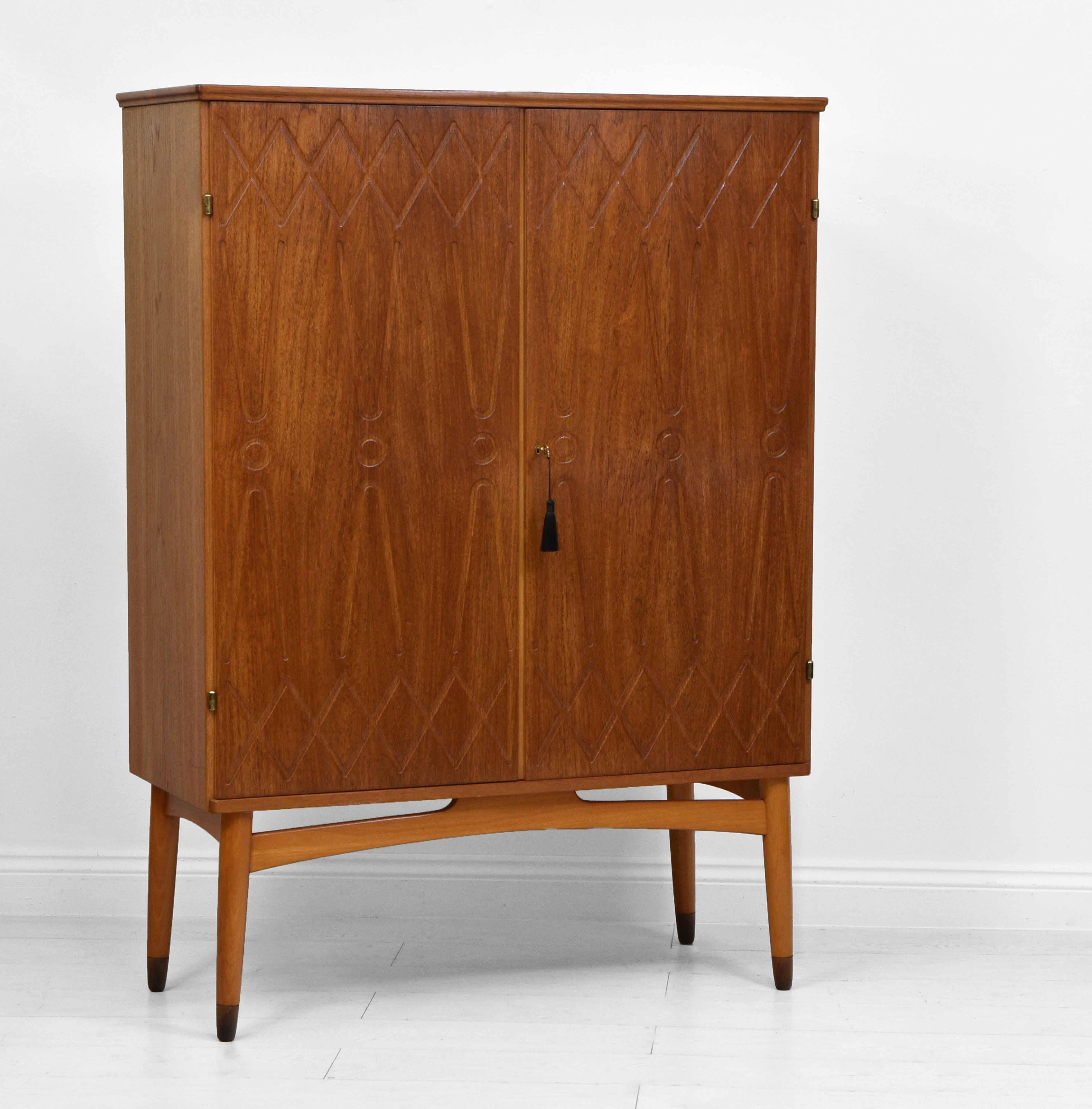 Mid century Scandinavian teak cabinet with geometric relief design on the doors. Attributed to Swedish designer Kirke Nielsen for Abrahamssons Möbelfabrik. Circa 1950s.

Overall in very good condition, showing some light marks in places.

The