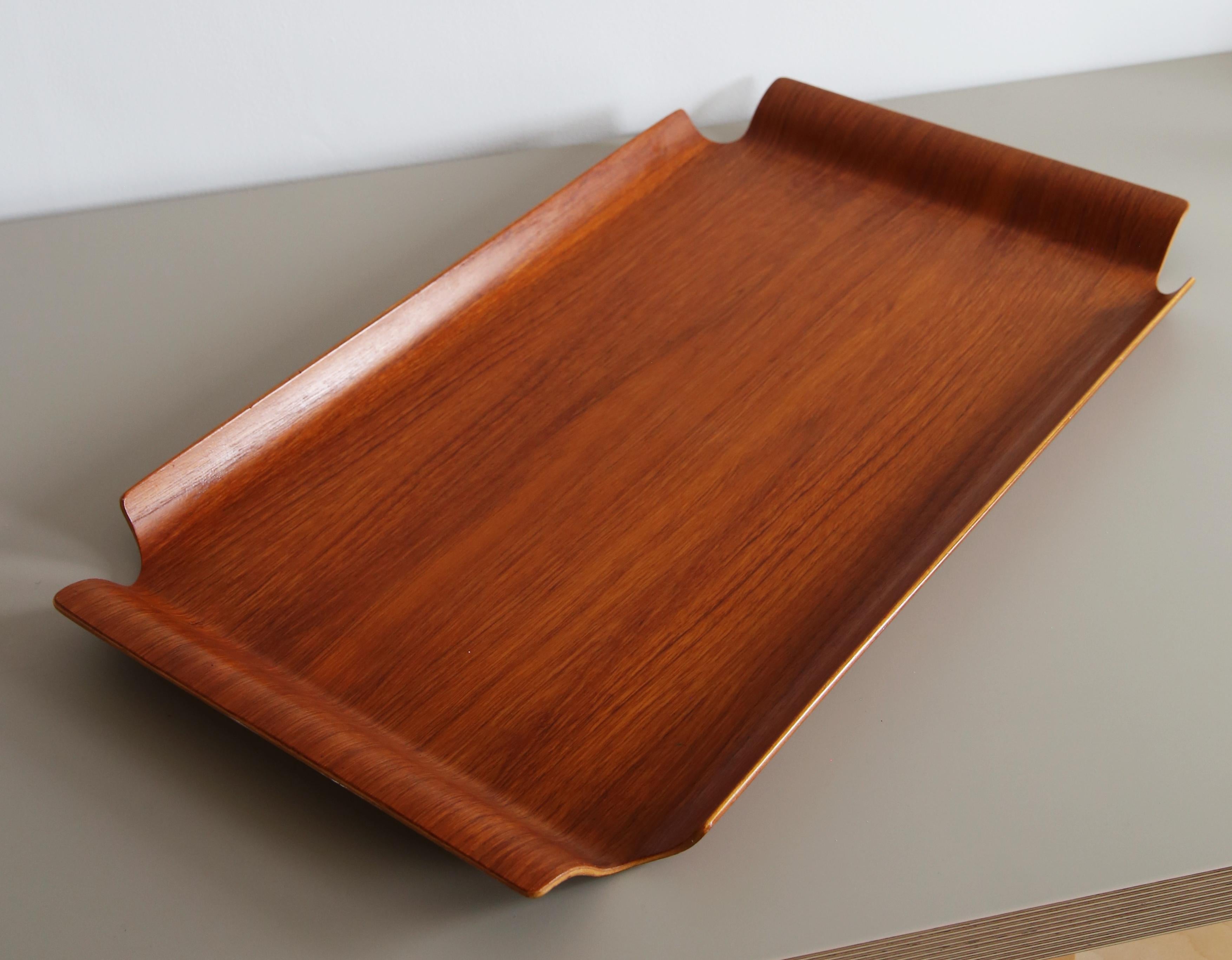 Lovely Mid Century Swedish bentwood teak tray designed by Bertil Fridhagen (Sweden 1905-1993) for Bodafors, dated 1960

Distinctive form with sloping handle borders on all sides with cut-out corners, made from a single sheet with gentle curved up