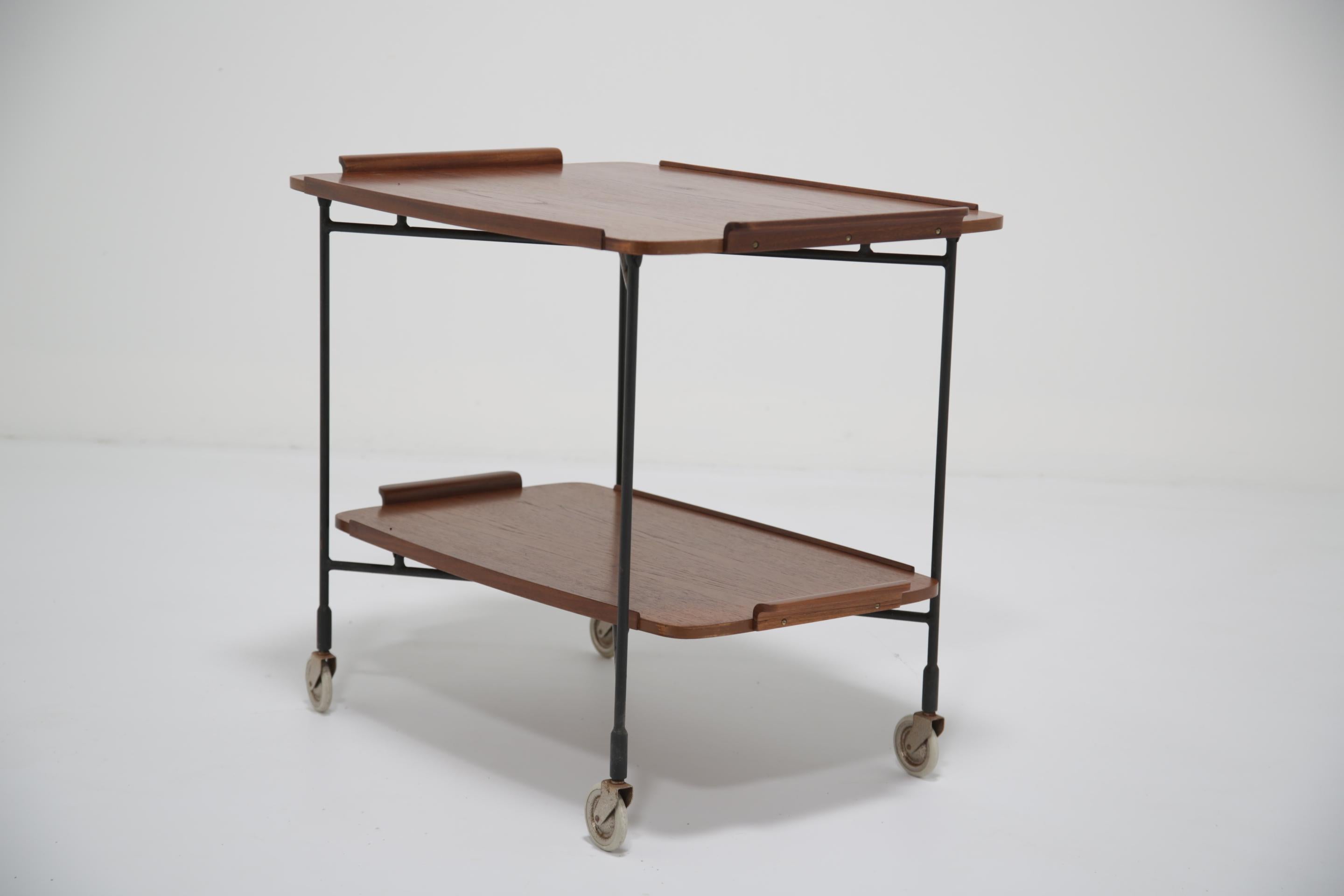 Añade un toque de elegancia escandinava a tu espacio con este versátil carrito para servir, fabricado en la década de 1950 por la empresa de diseño sueca Firma Glas & Tra (traducido a Vidrio y Madera). Fabricado con rica madera de teca y duradero