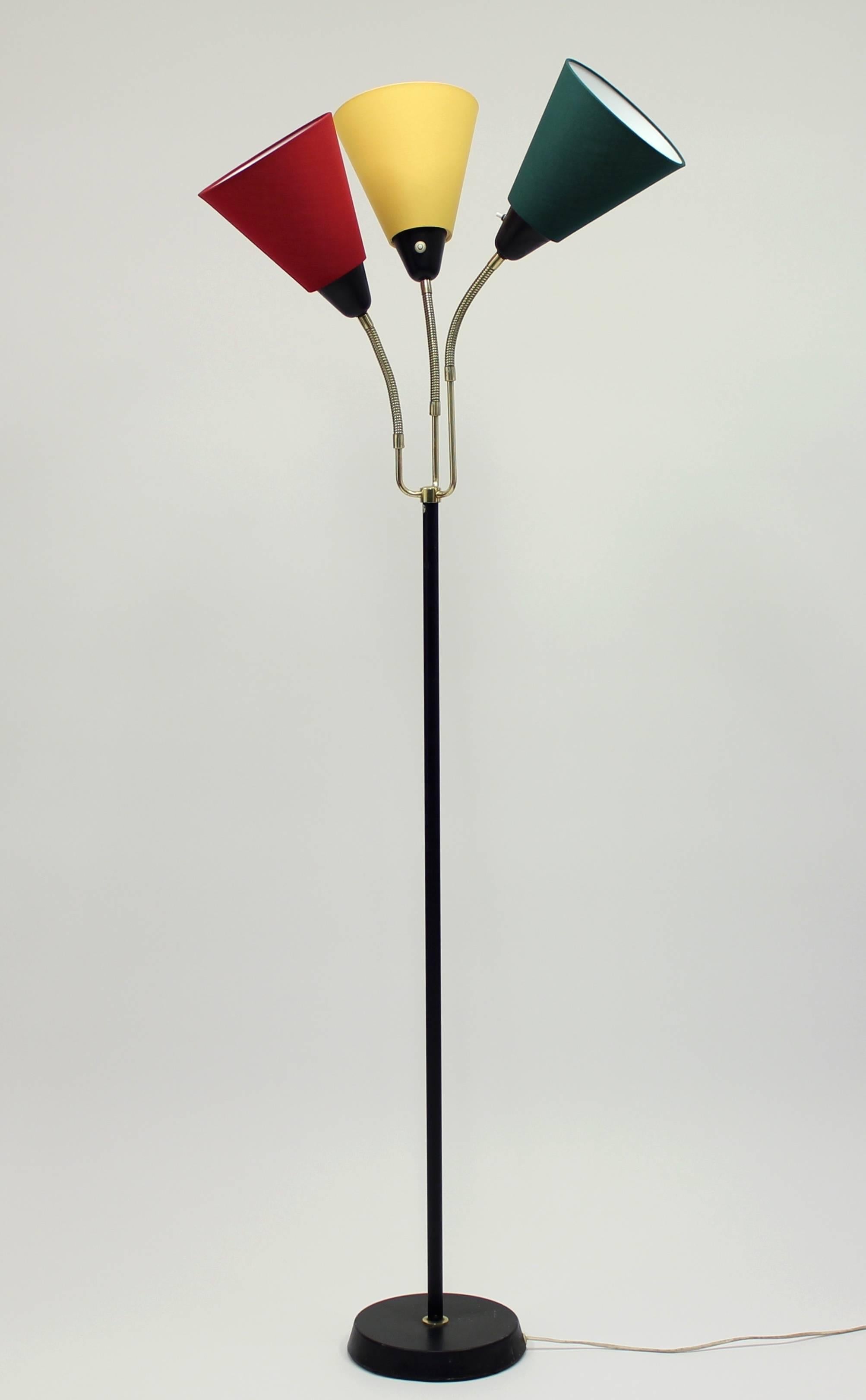 This Swedish midcentury three-light floor lamp was manufactured in the 1950s-1960s. It is made from brass and black metal with three new shades. The three lights have gooseneck arms that are set at slightly different heights with a light switch on